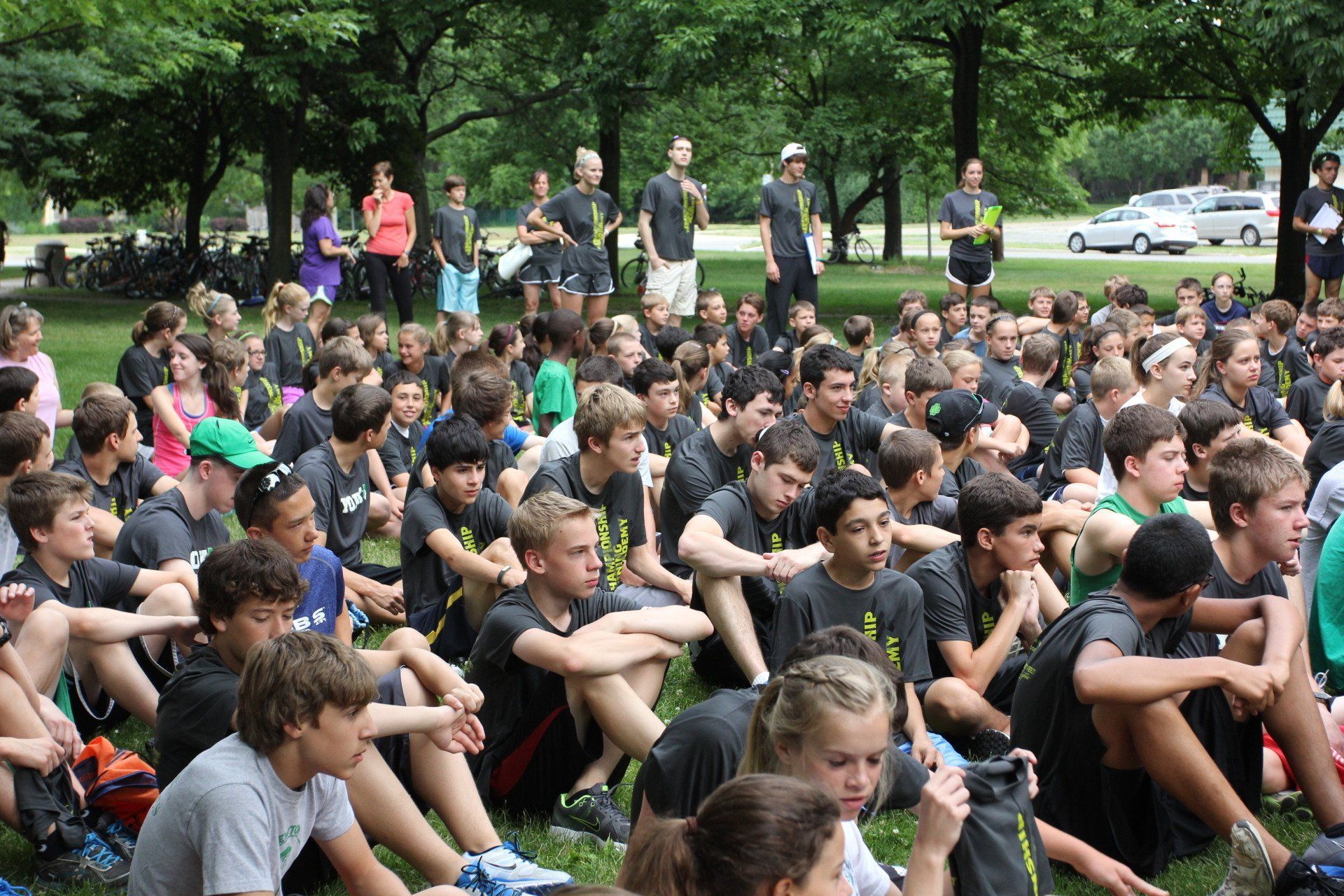 A large group of people are sitting on the grass in a park