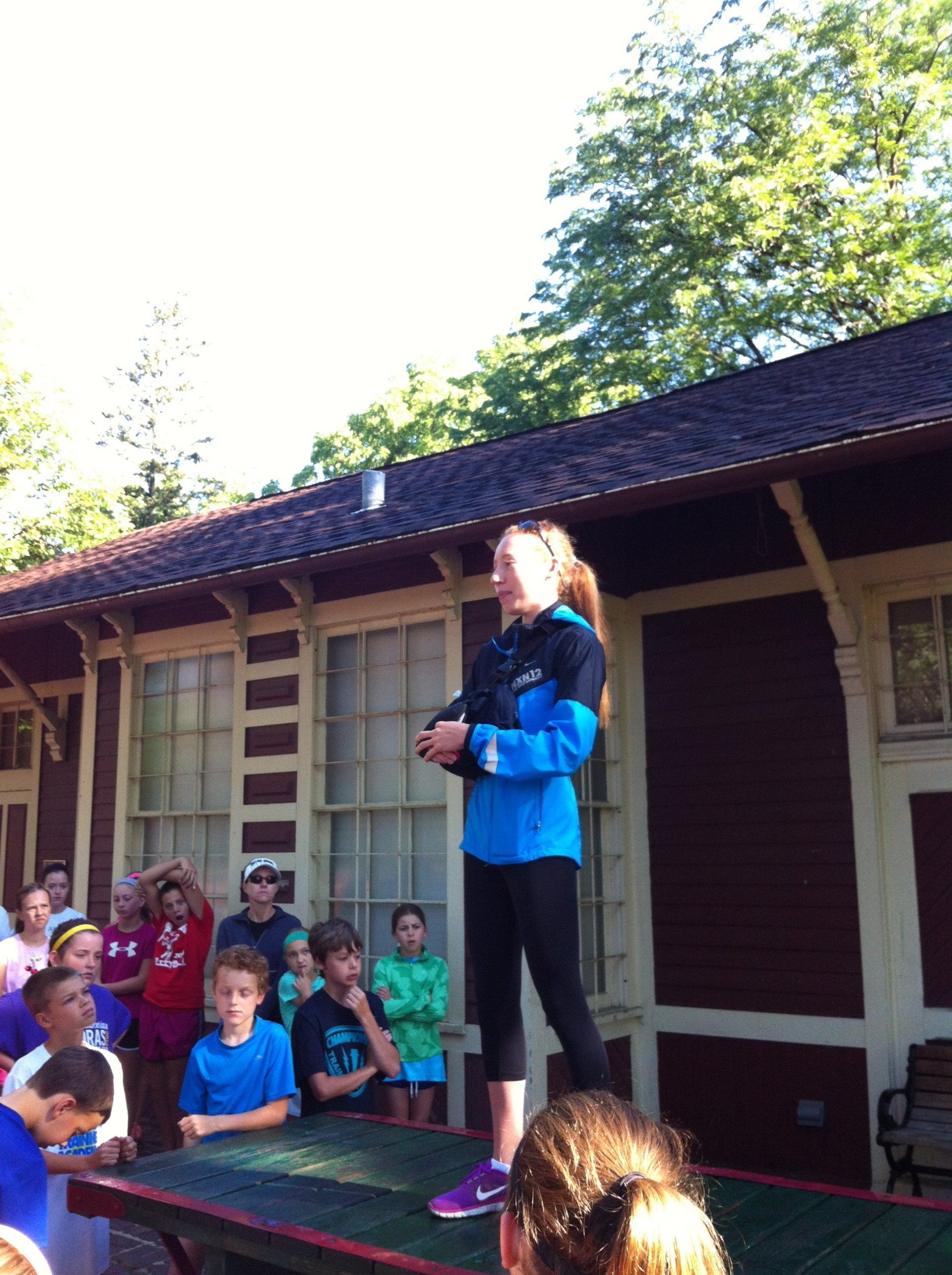 A girl in a blue jacket is standing in front of a crowd