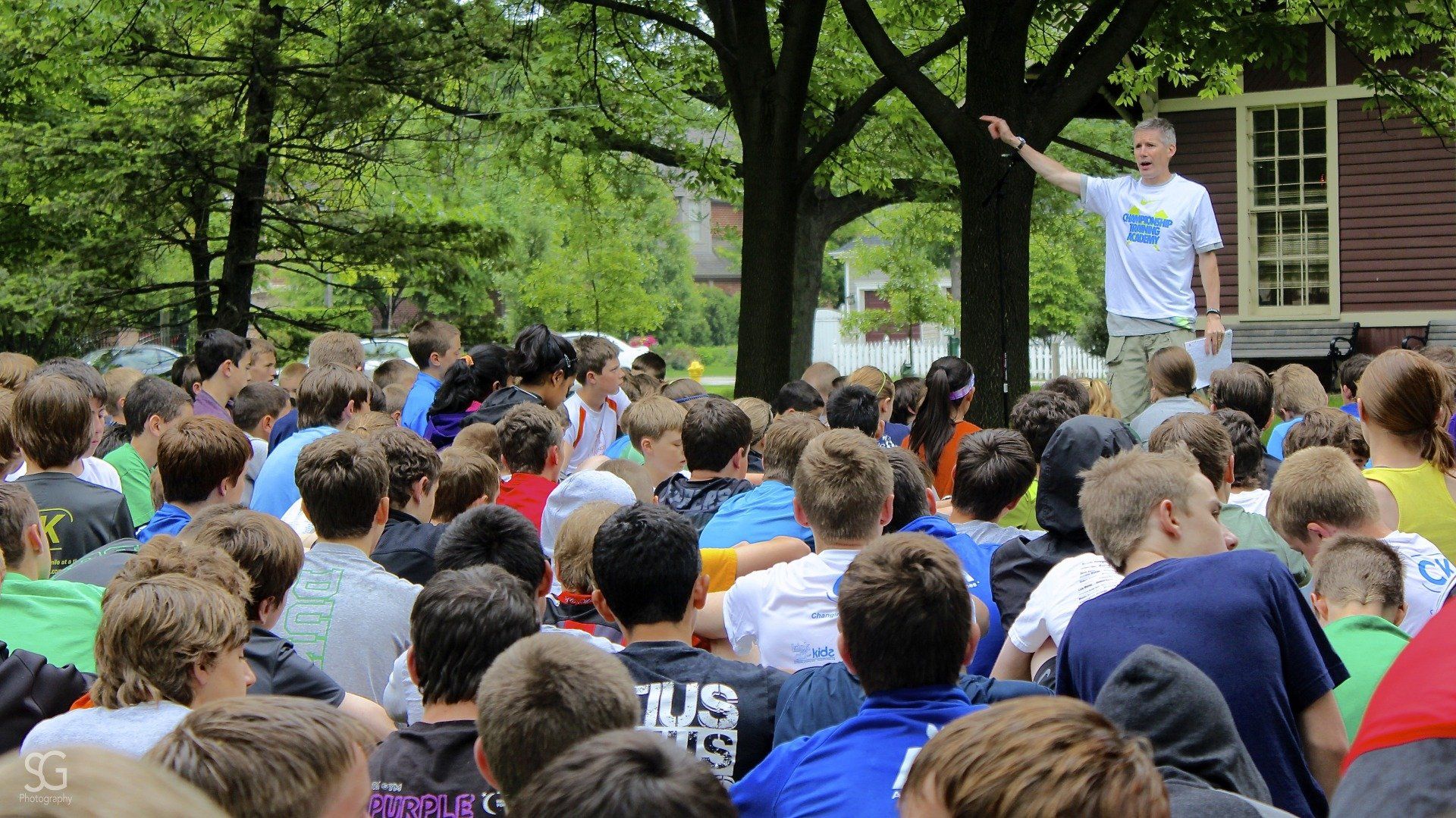 A man is standing in front of a large group of people.
