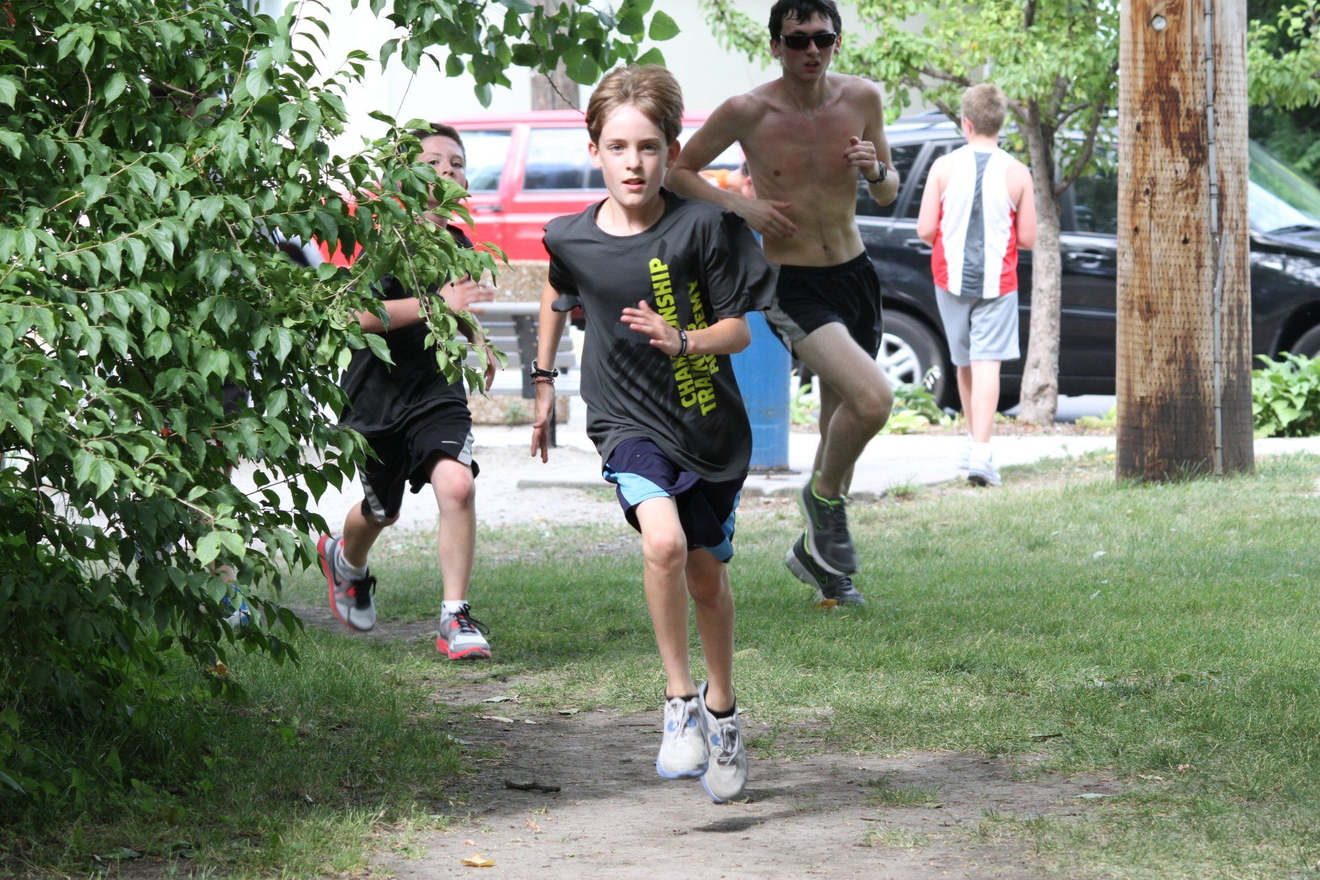 A boy wearing a shirt that says reebok is running in a park