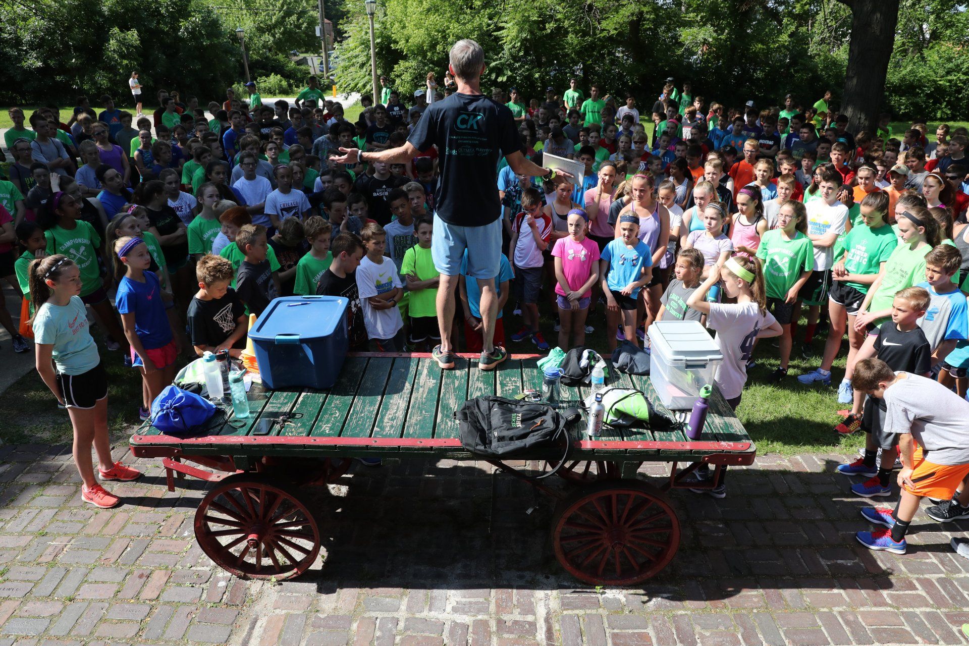 A man is standing on a cart in front of a large group of people.