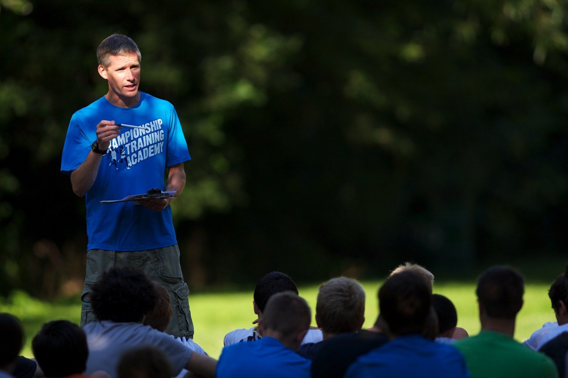A man in a blue shirt is standing in front of a group of people.