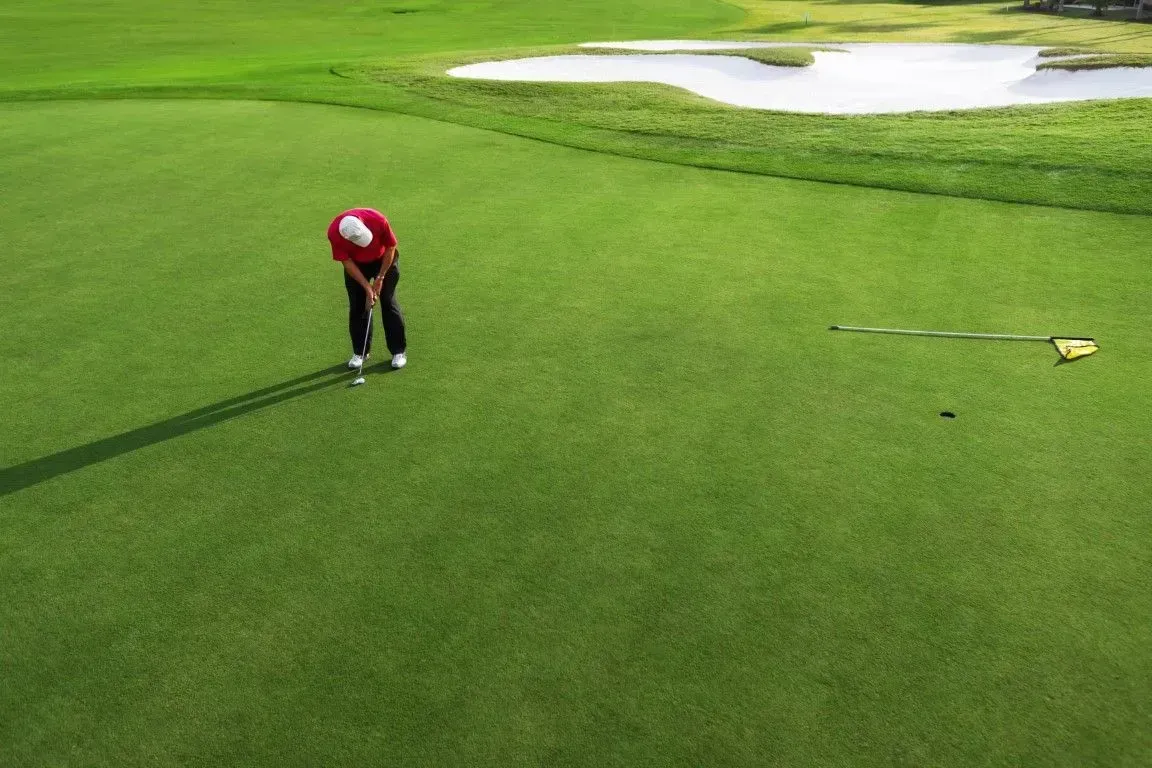 Golfer putting on synthetic green.