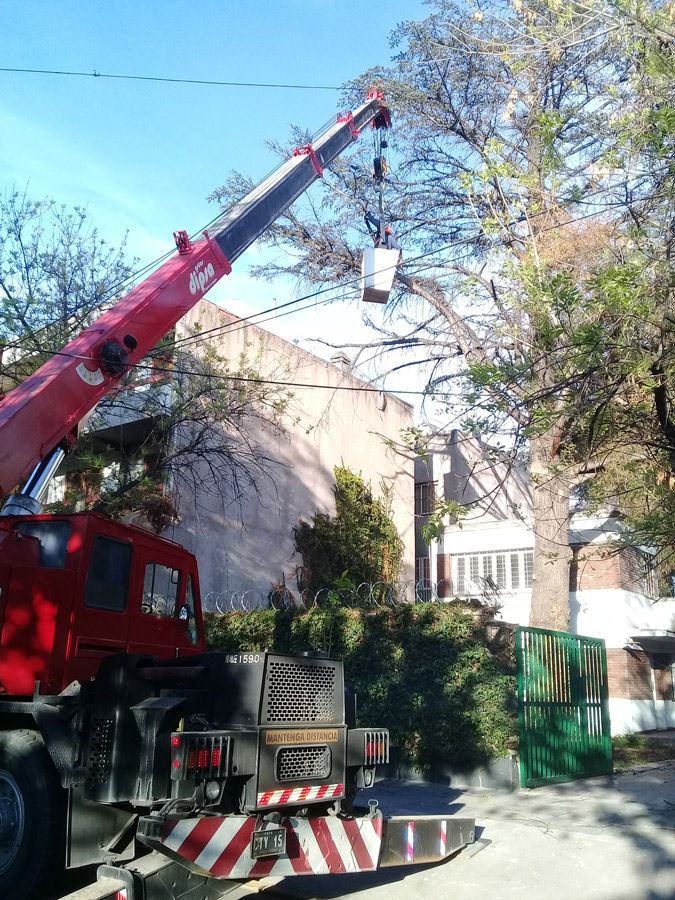 Un camión rojo con una grúa acoplada está estacionado al costado de la carretera.