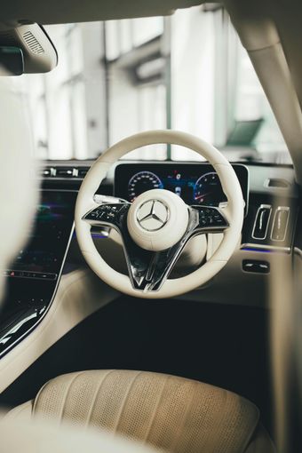Interior view of a white Mercedes car with a white steering wheel and a digital dashboard.