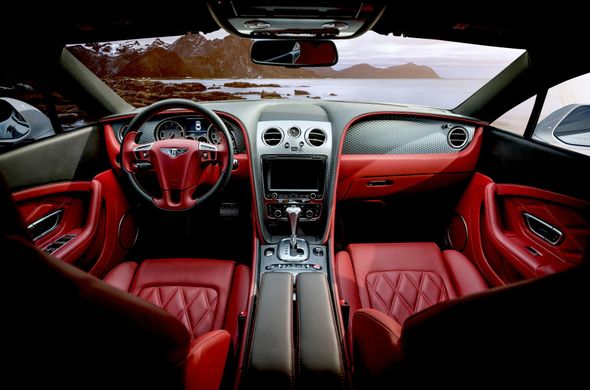 Red leather interior of a luxury car with a view of the sea and mountains.