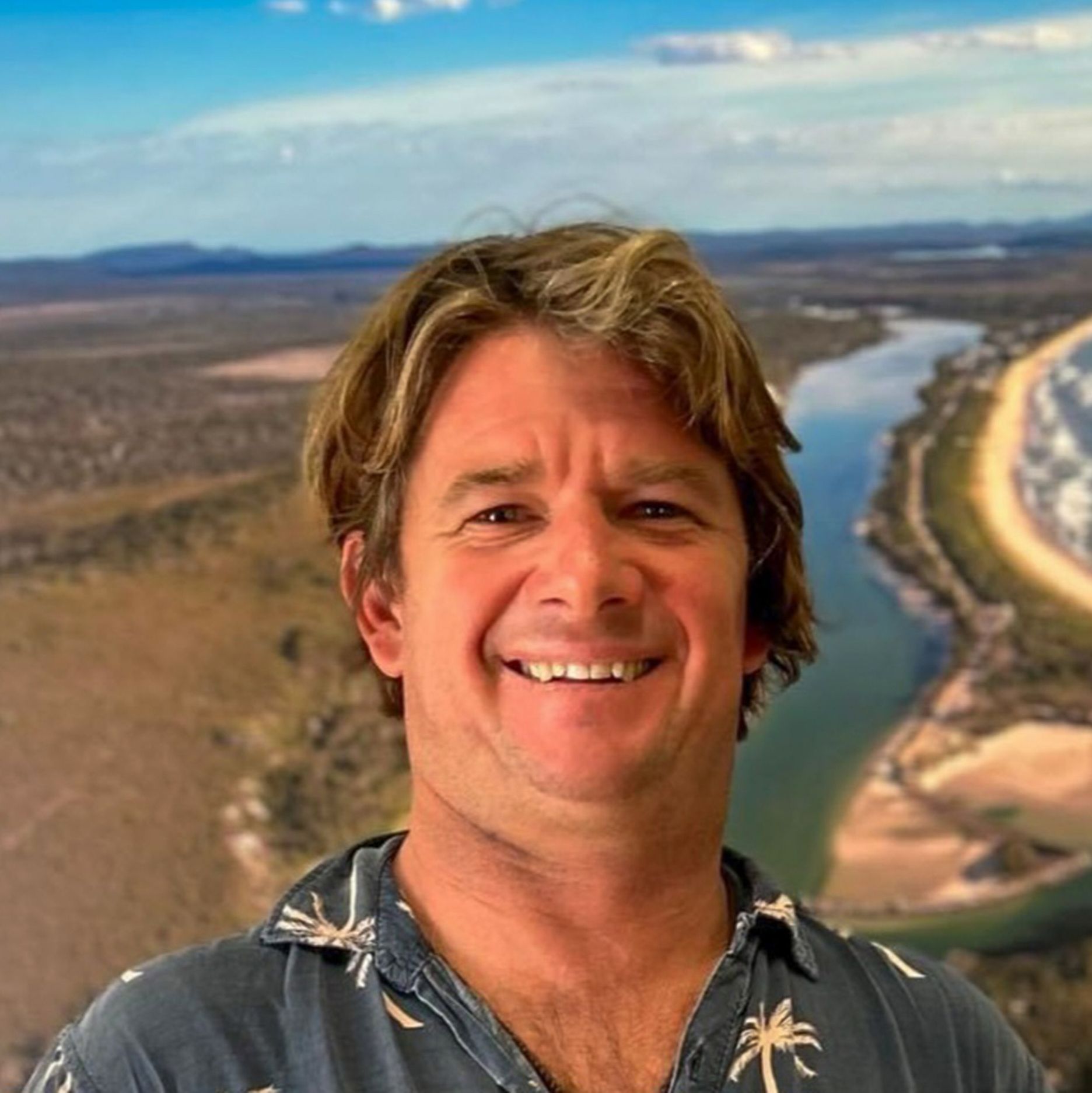 Mark Pilkie - Osteopath Bust shot of smiling man standing in front of scenic photo
