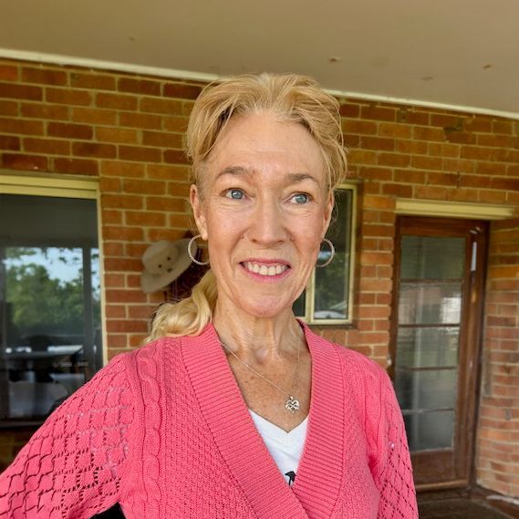 Mary Anne Lowery - Chiropractor Smiling lady standing in front of brick wall with windows and door