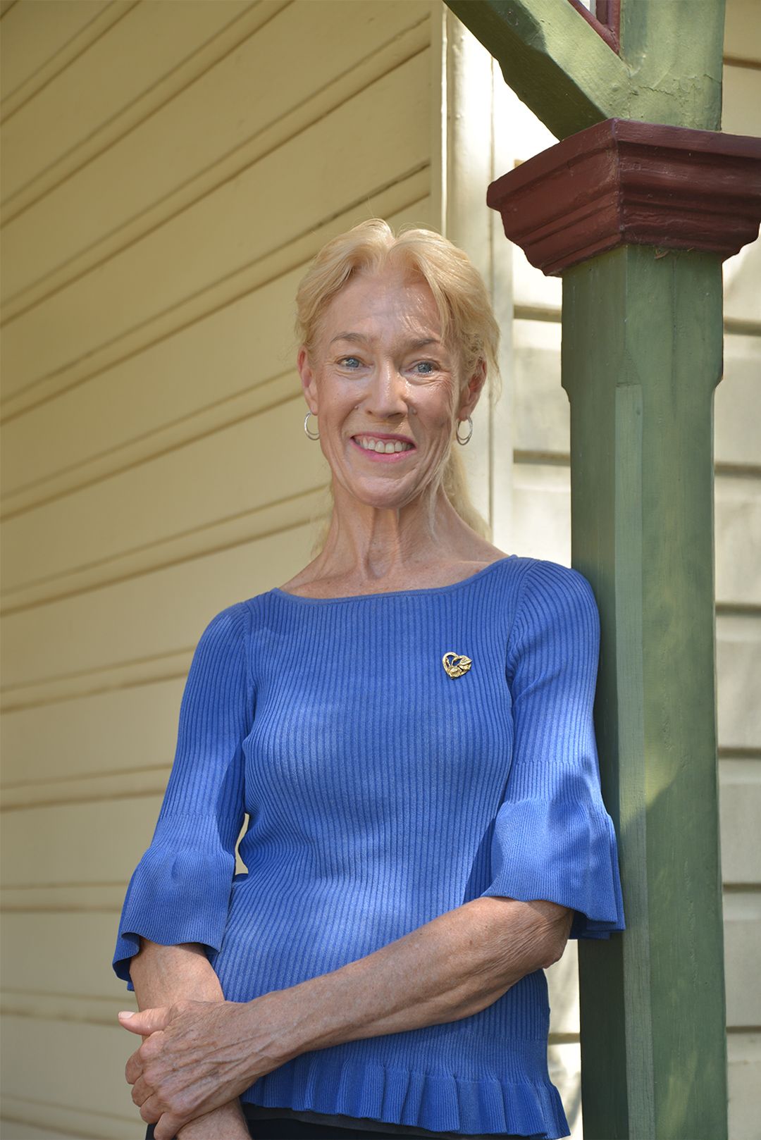 Smiling lady standing in front of brick wall with windows and door