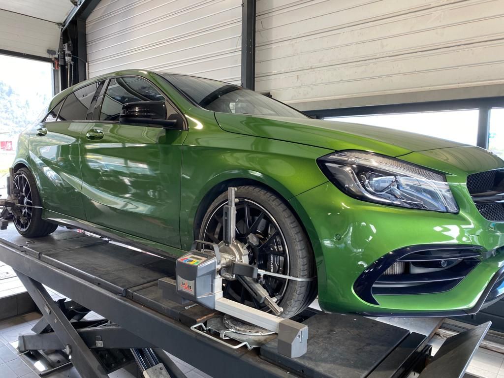 Une voiture verte est assise au sommet d’un ascenseur dans un garage.