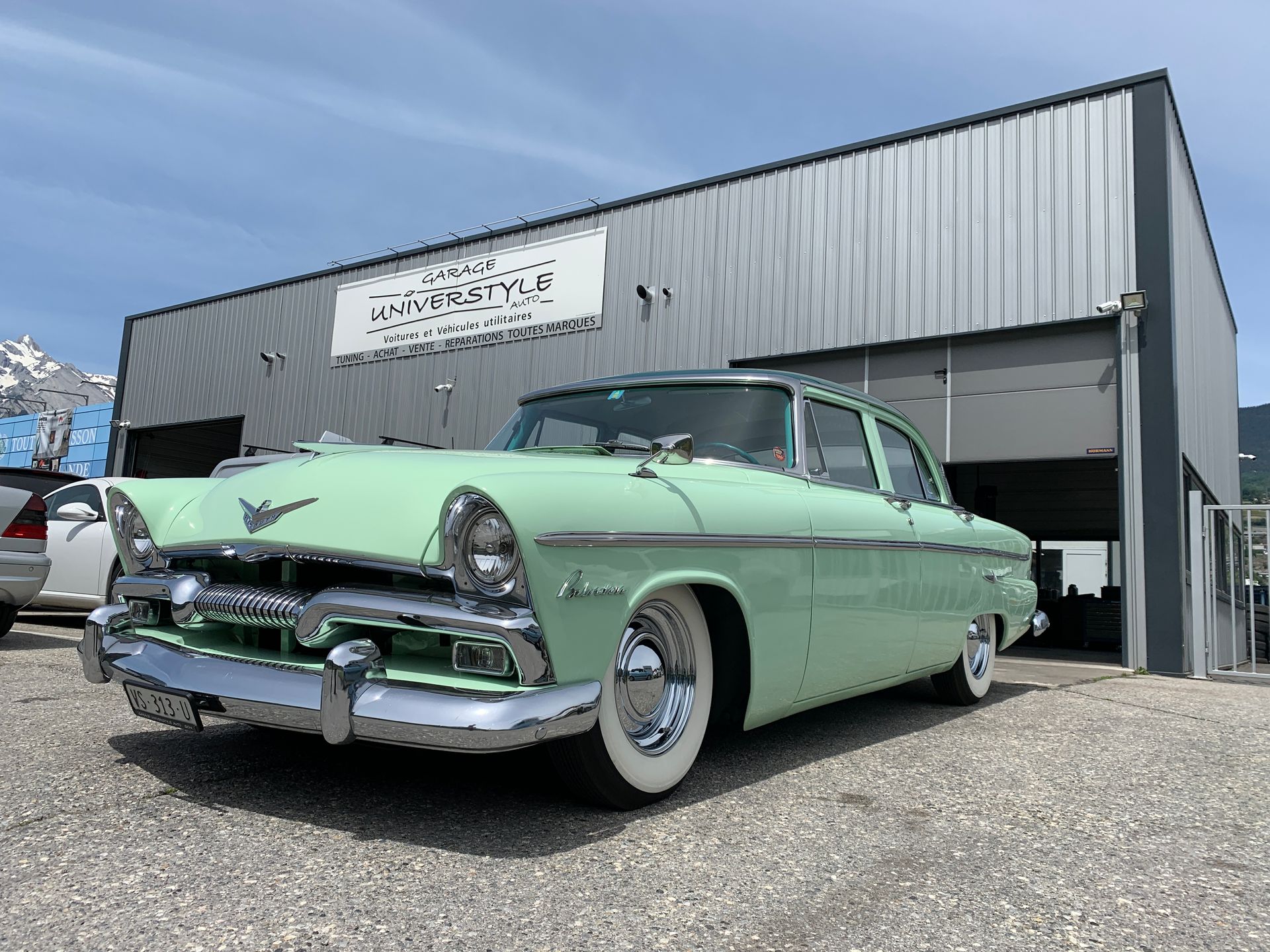 Une voiture verte est garée devant un immeuble.