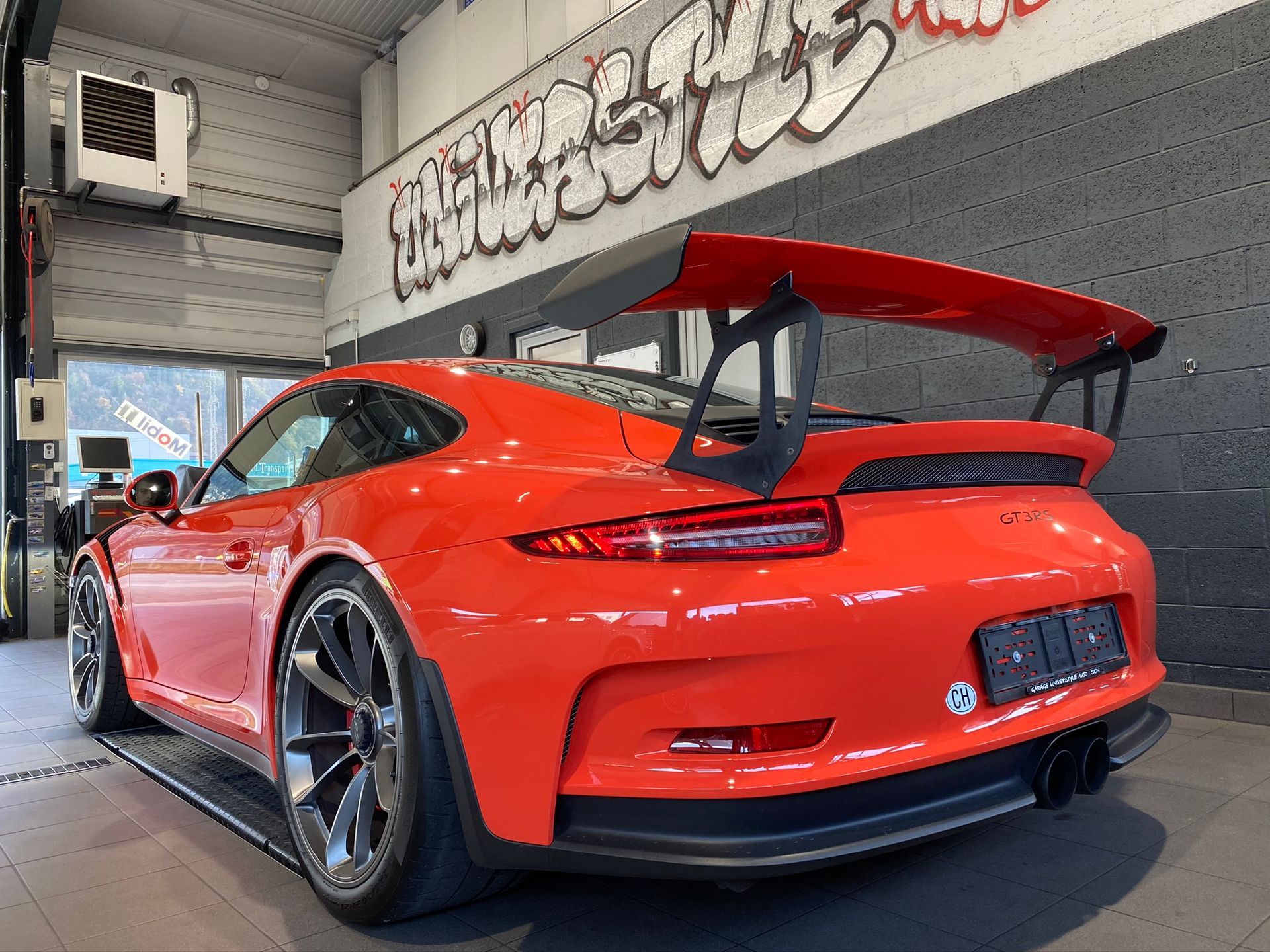 Une porsche 911 gt3 rs rouge est garée dans un garage.