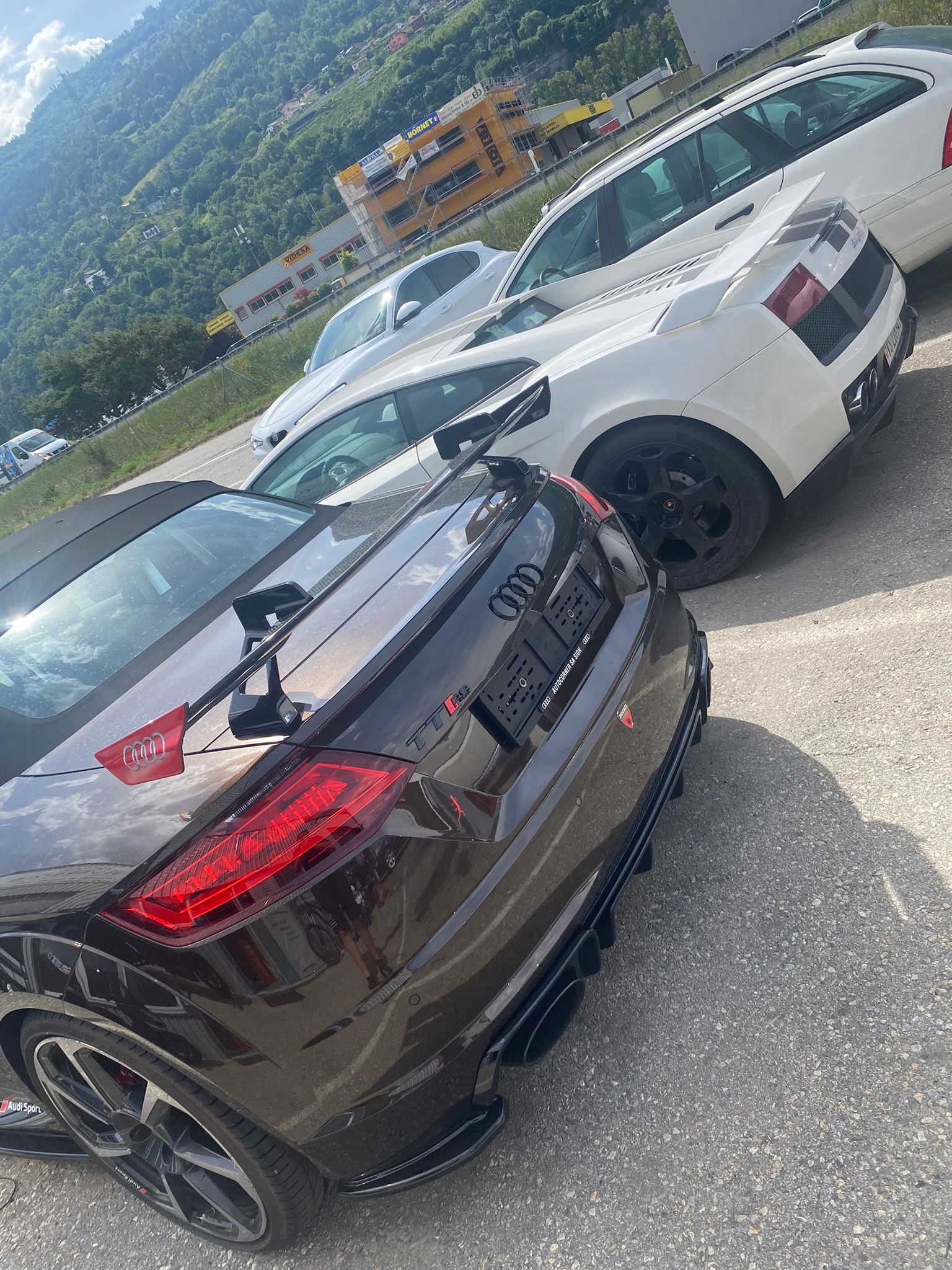 Une voiture noire est garée à côté d’une voiture blanche dans un parking.