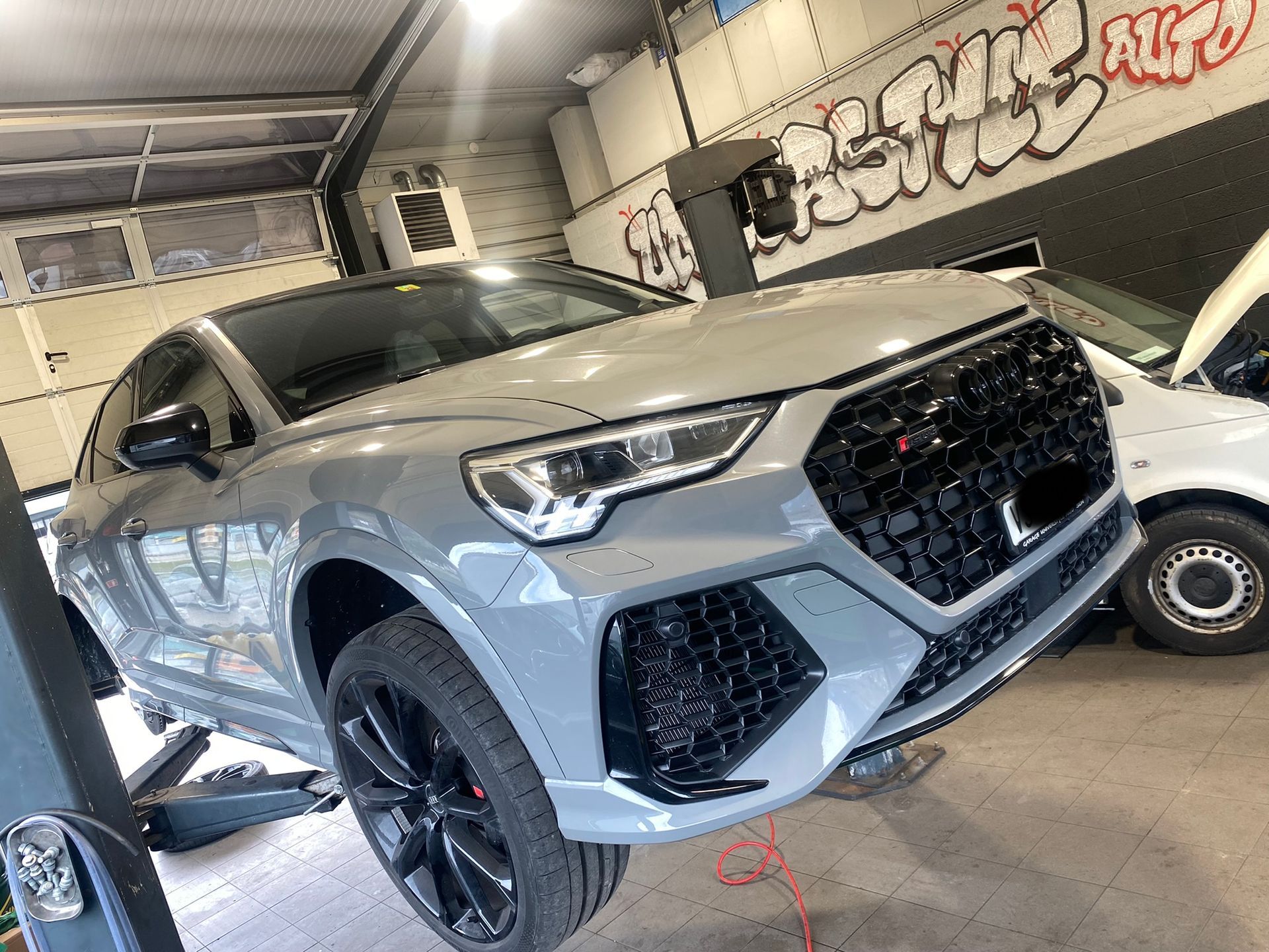 Une voiture est posée sur un ascenseur dans un garage.