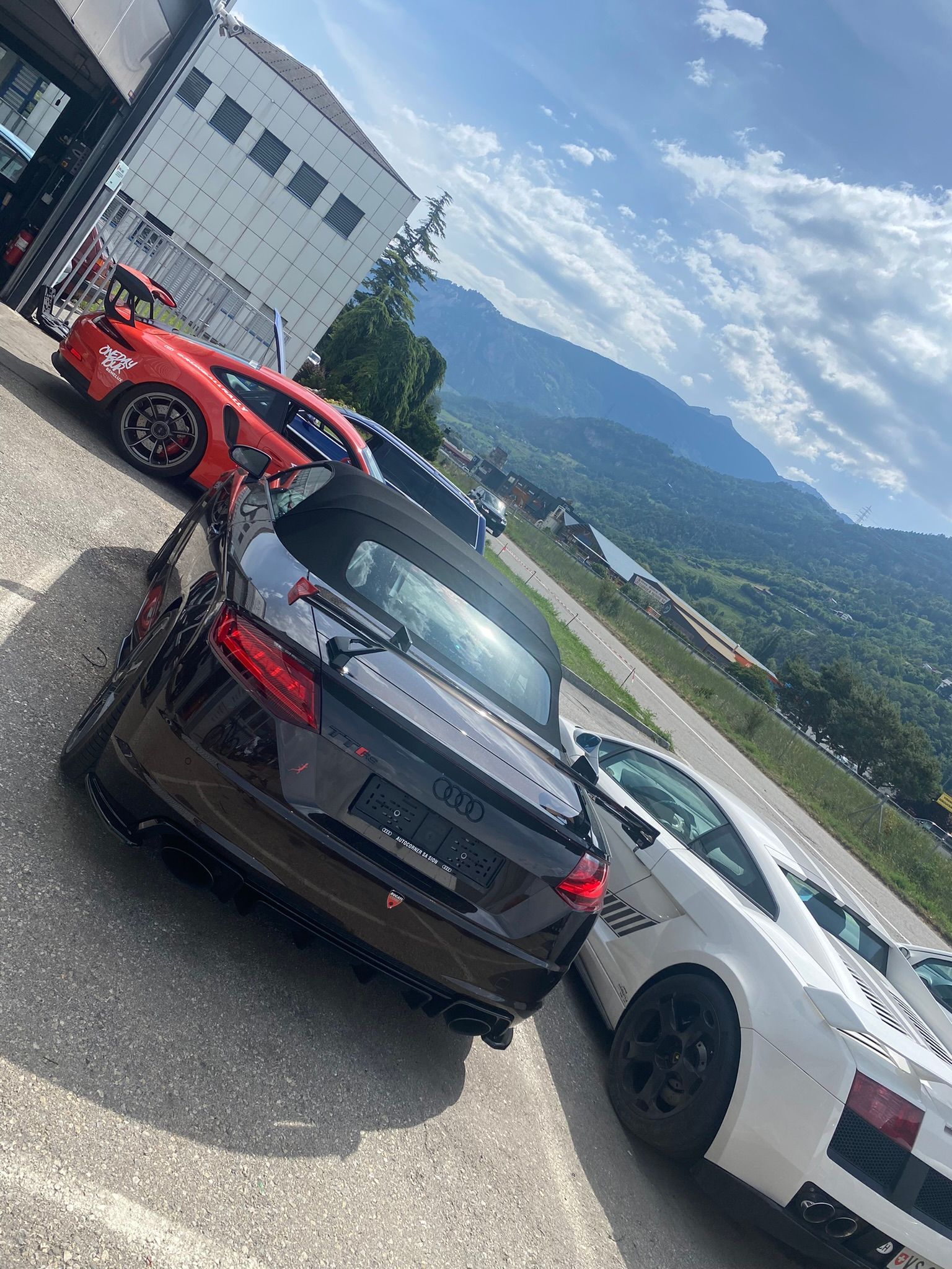 Un groupe de voitures sont garées les unes à côté des autres dans un parking.