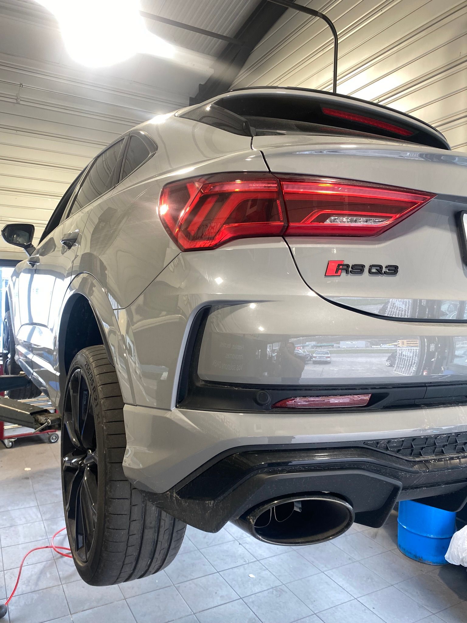 Une Audi Q3 RS argentée est garée dans un garage.