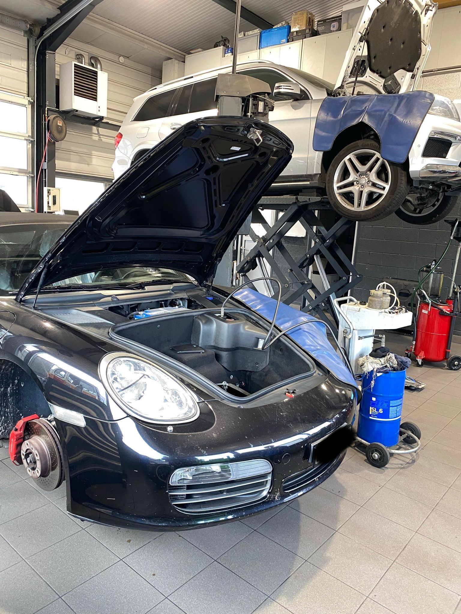 Une voiture de sport noire avec le capot ouvert se trouve dans un garage.