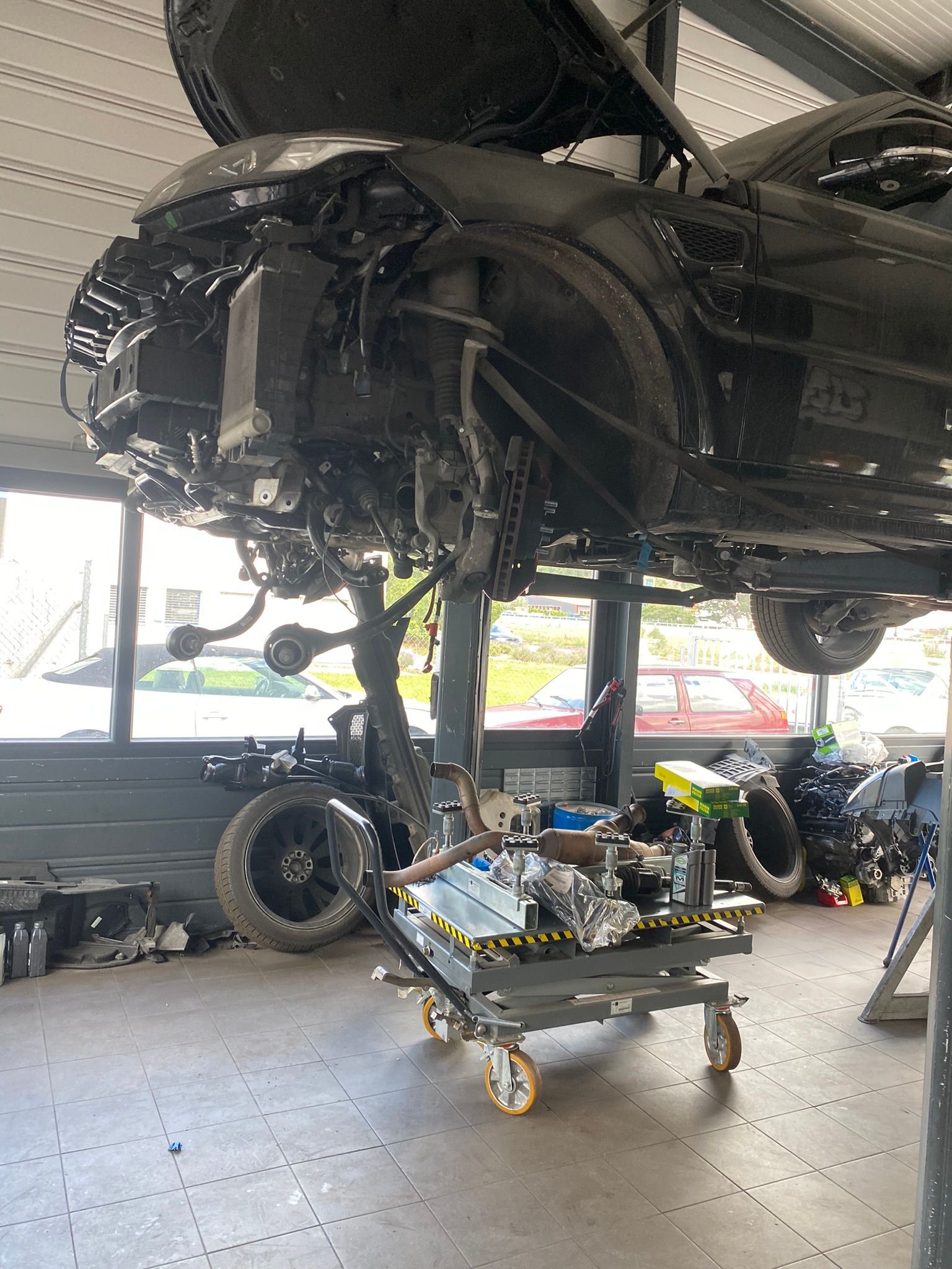 Une voiture est en travaux dans un garage.