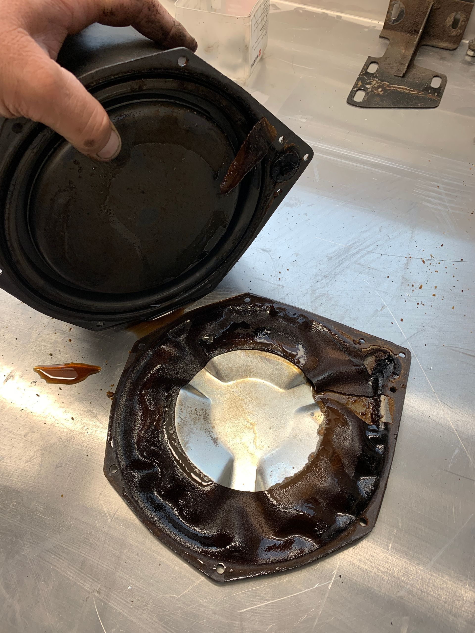 Une personne tient un haut-parleur sale sur une surface métallique.