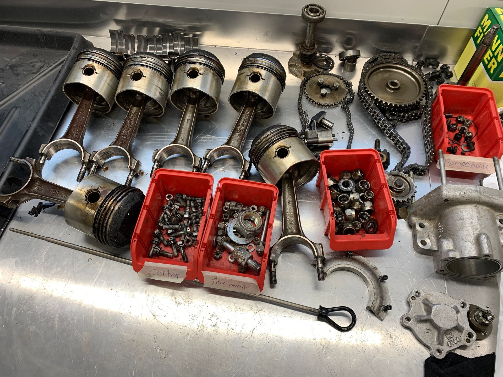 Un tas de pistons et d’autres pièces sont posés sur une table.