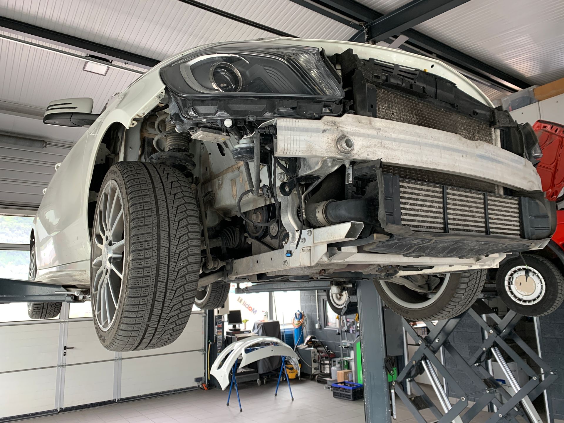 Une voiture blanche est assise sur un ascenseur dans un garage.