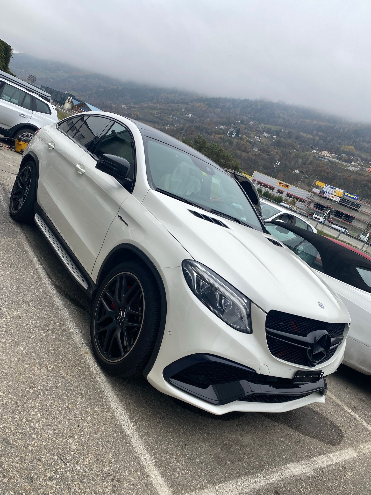 Une Mercedes Benz gle 63 AMG blanche est garée dans un parking.