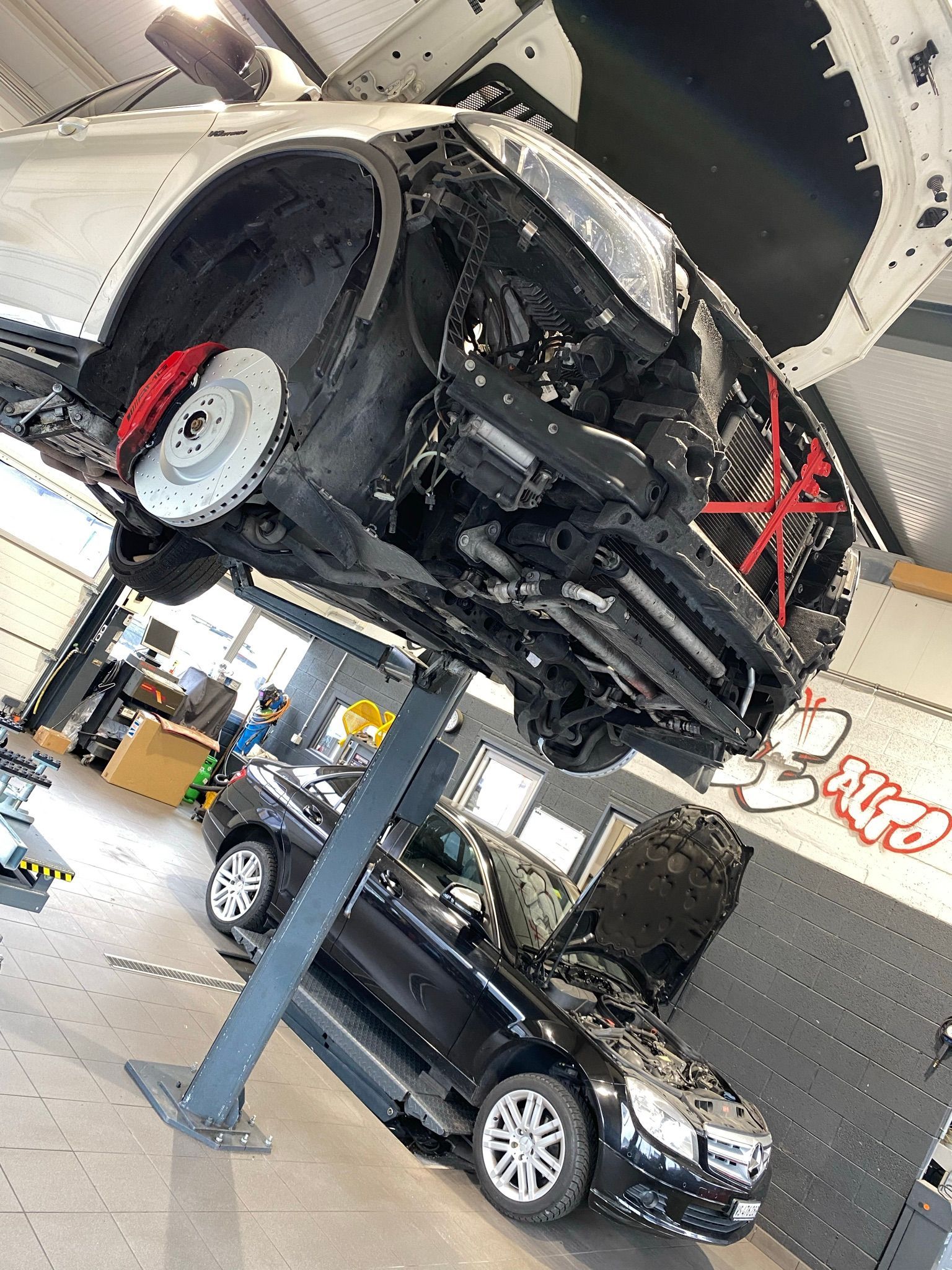 Une voiture est posée au sommet d’un ascenseur dans un garage.