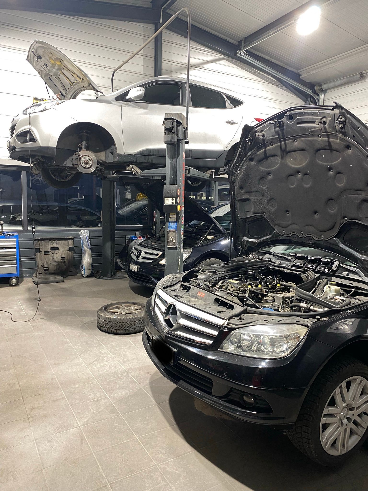 Une voiture noire est garée dans un garage avec le capot ouvert.