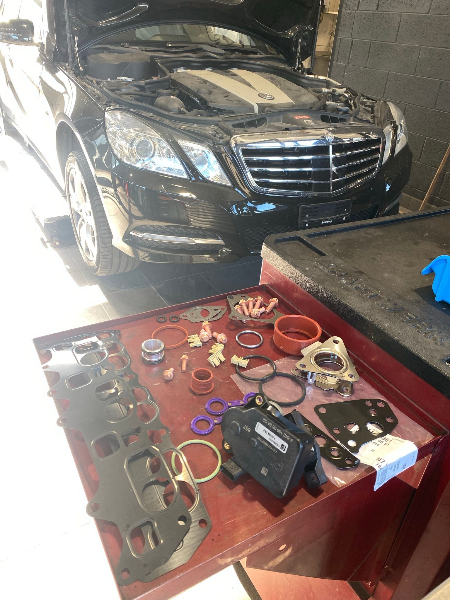 Une Mercedes Benz noire est garée dans un garage avec son capot relevé.