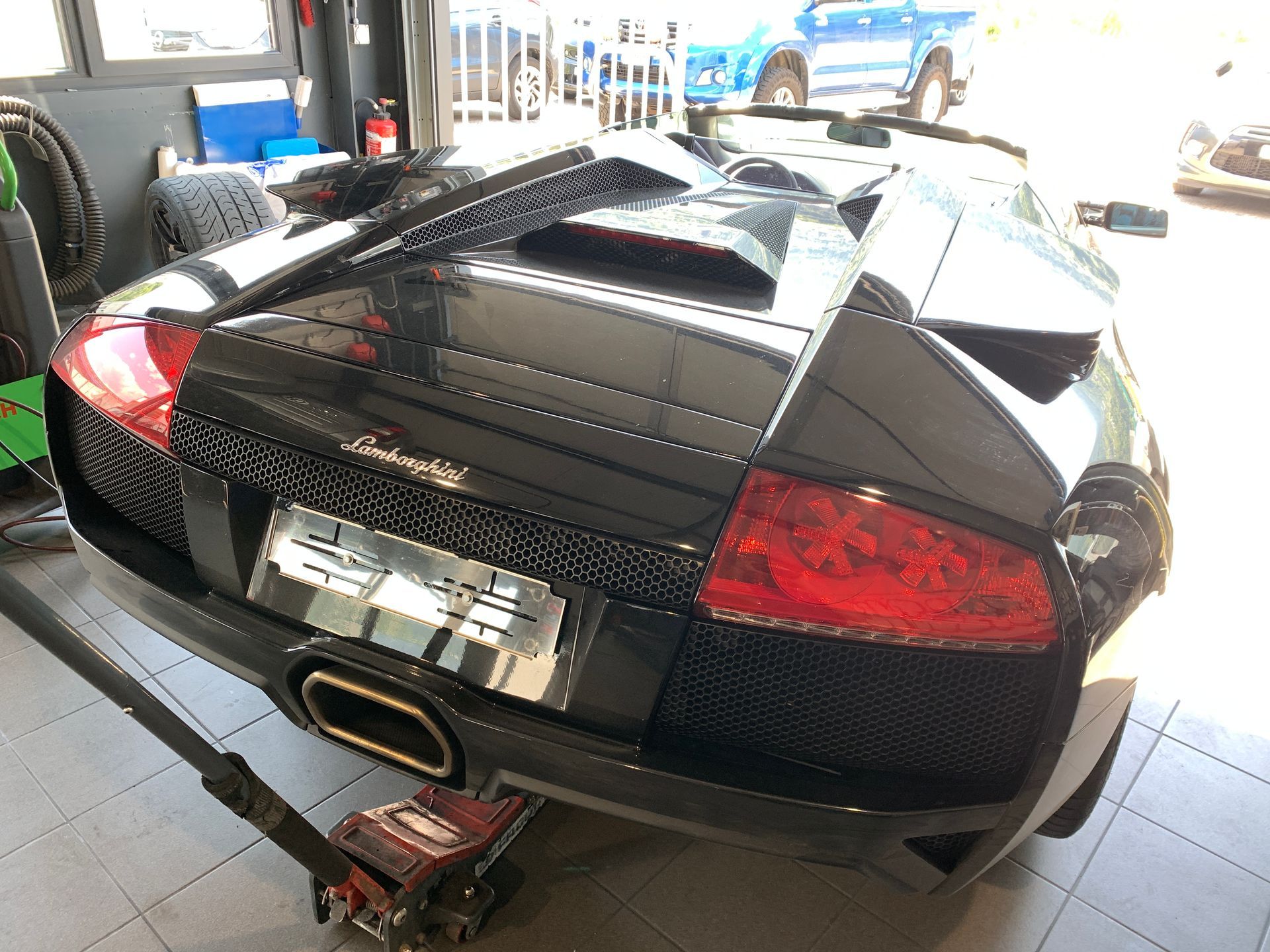 Une voiture de sport noire est assise sur un cric dans un garage.