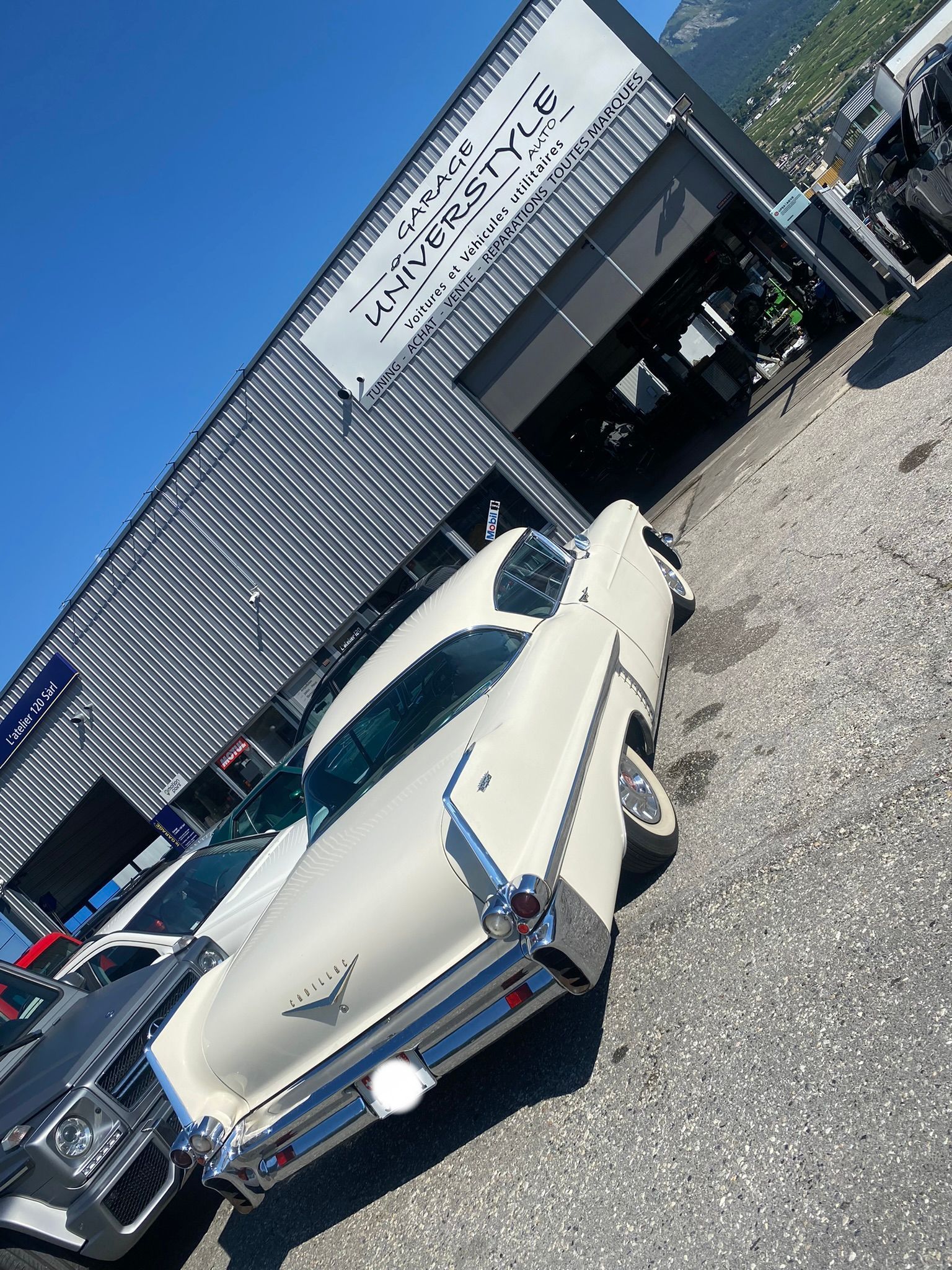 Une voiture blanche est garée devant un immeuble.