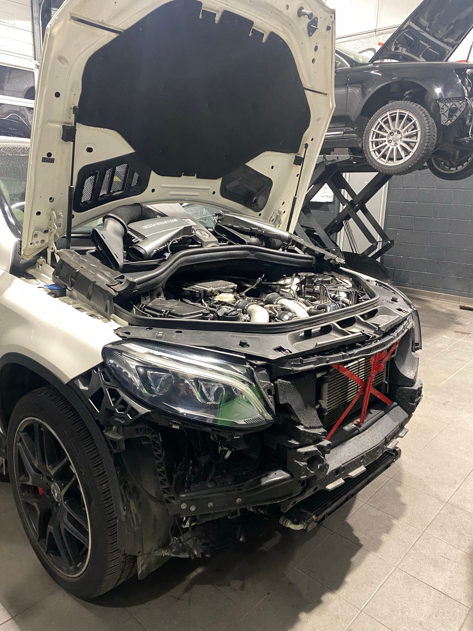 Une voiture blanche avec le capot ouvert est assise dans un garage.