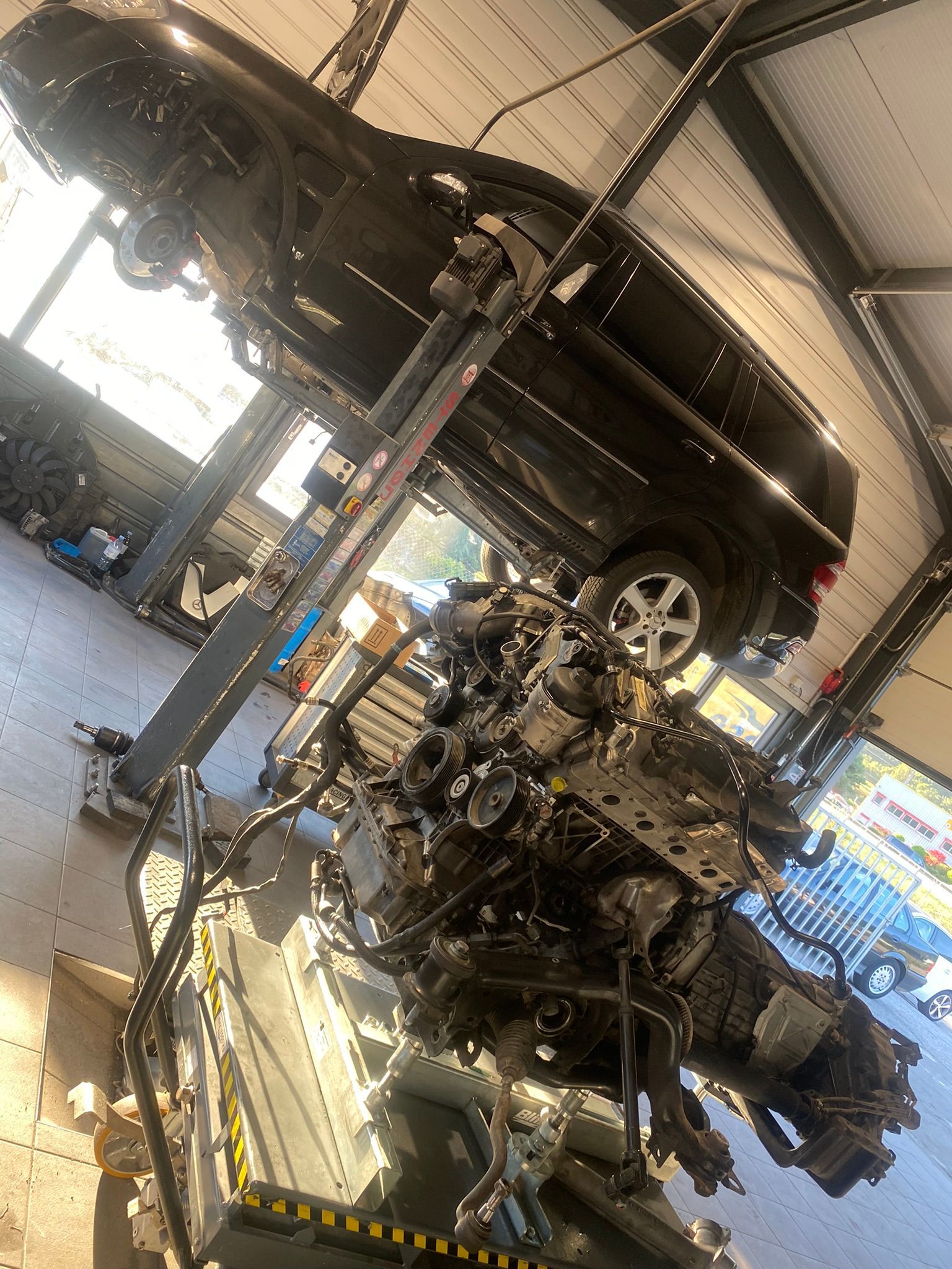Une voiture repose sur un gros moteur dans un garage.