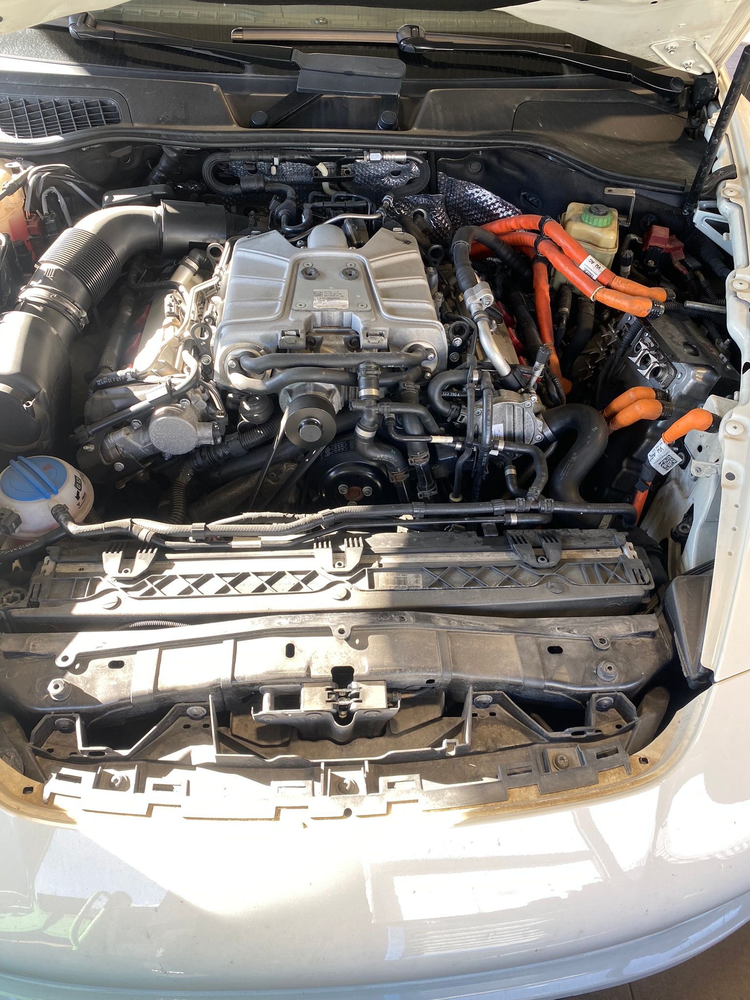 Le moteur d’une voiture blanche avec le capot ouvert.