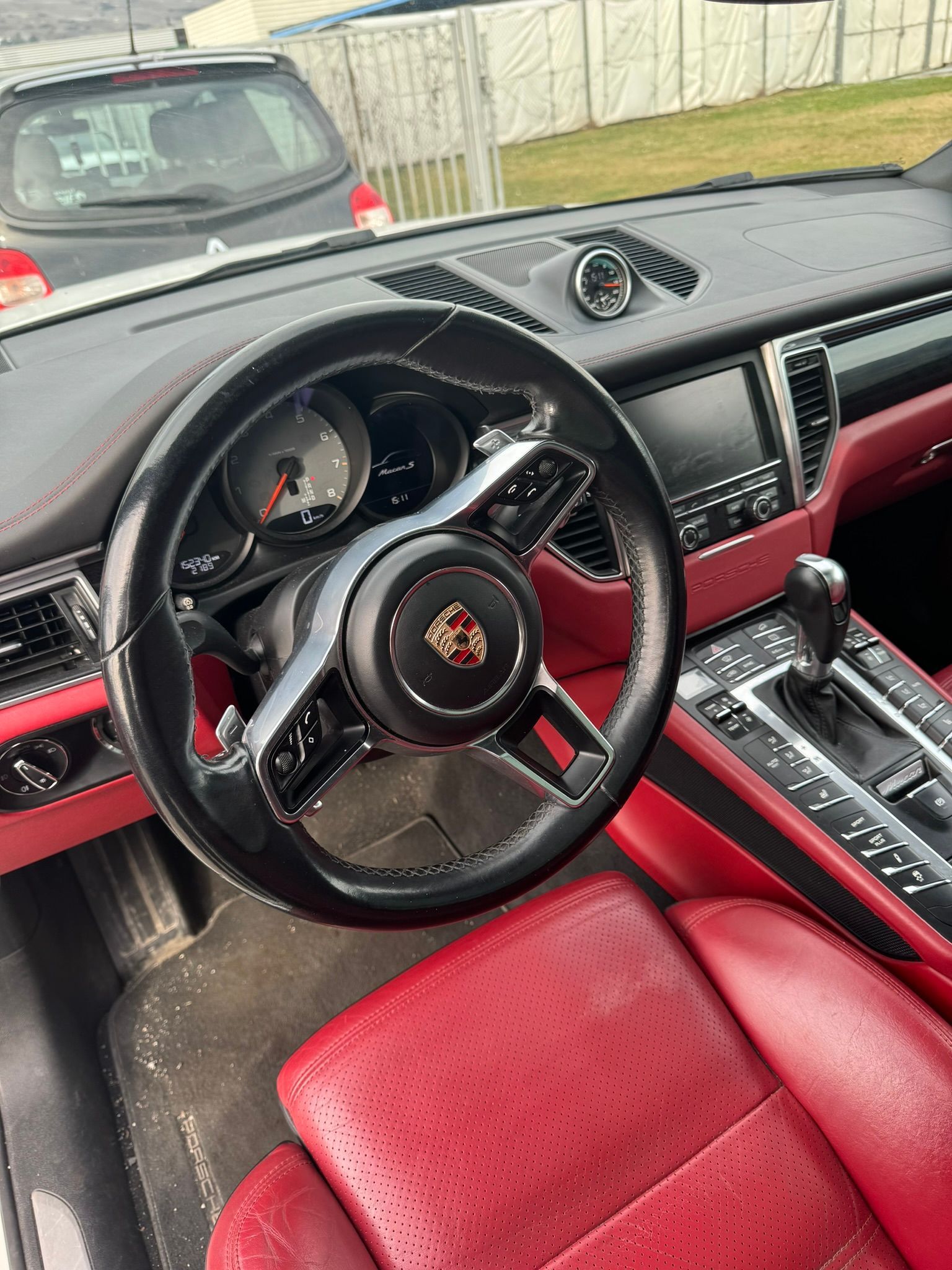 L'intérieur d'une porsche macan turbo avec des sièges rouges et un volant noir.