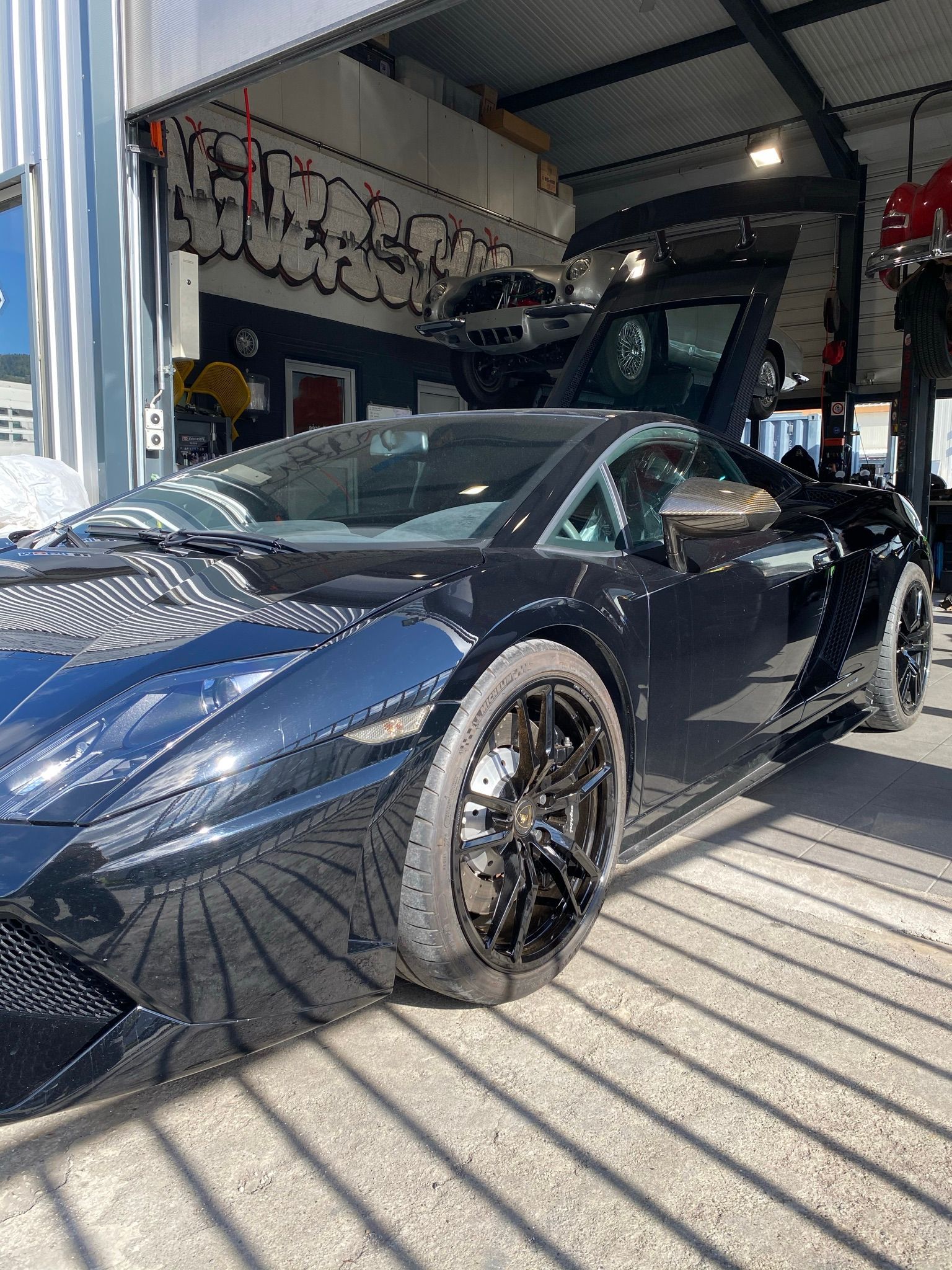 Une Lamborghini Gallardo noire est garée dans un garage.