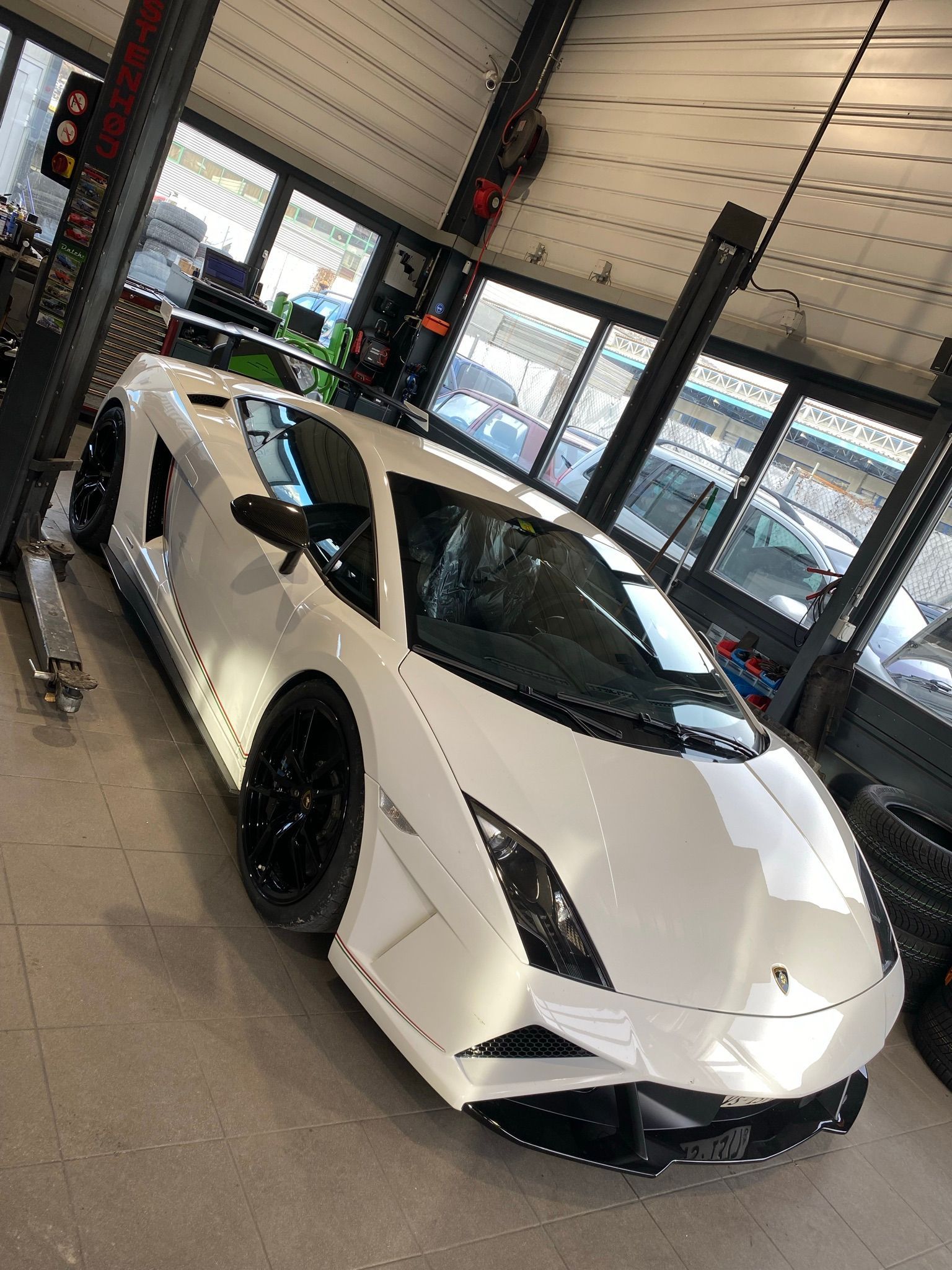 Une Lamborghini Aventador blanche est garée dans un garage.