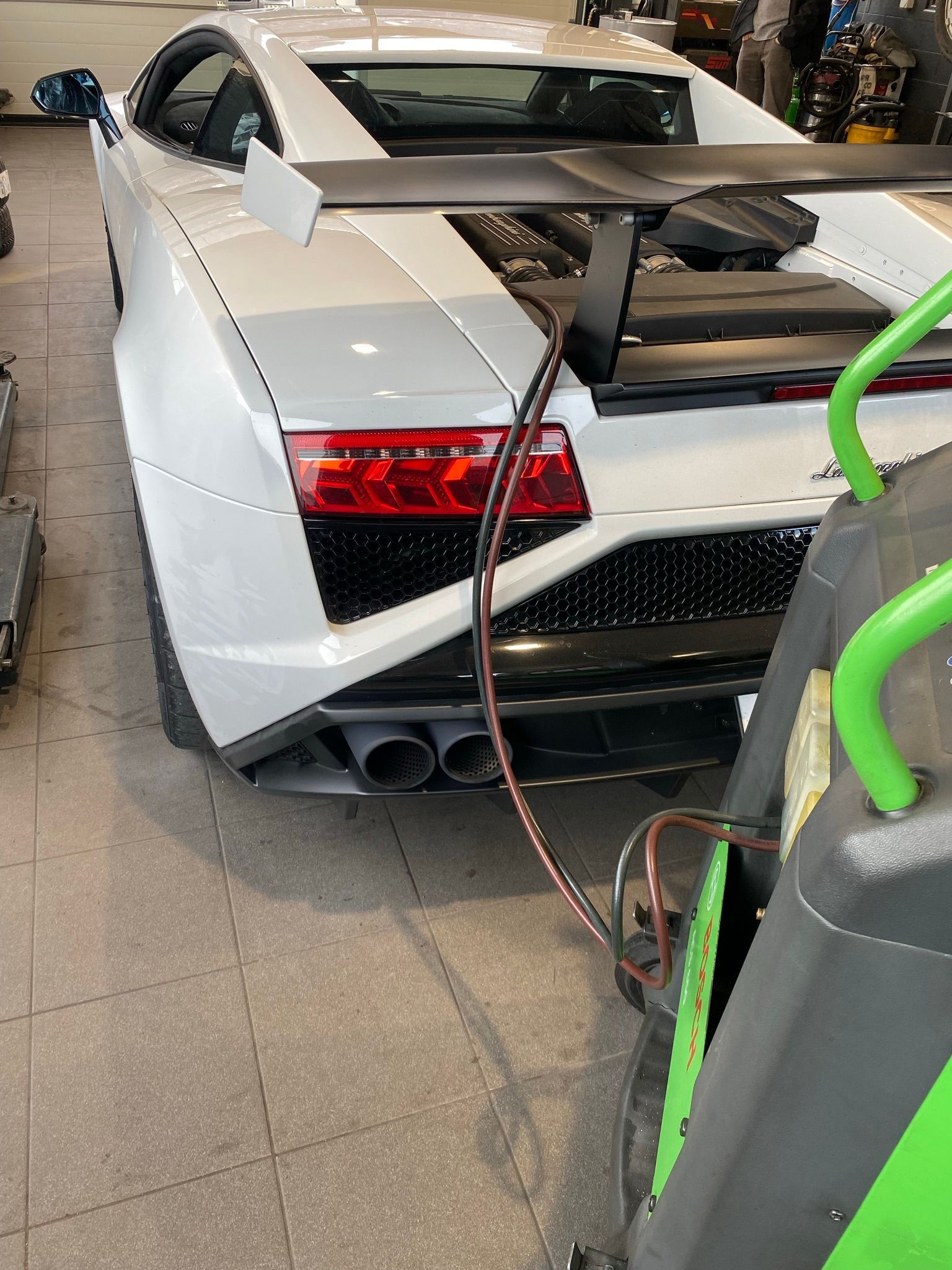 Une voiture de sport blanche est en cours d'entretien dans un garage.