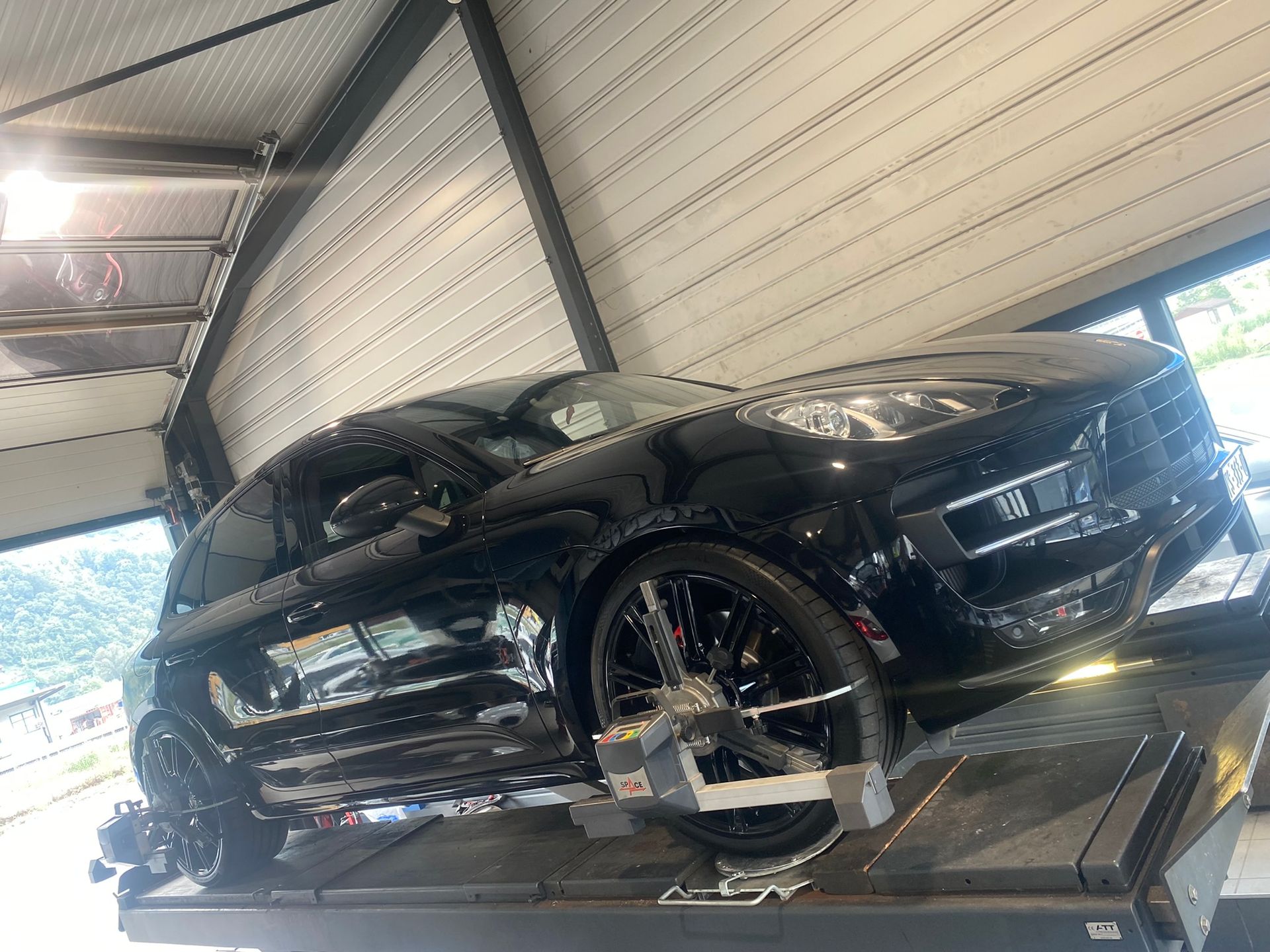 Une voiture noire est assise au sommet d’un ascenseur dans un garage.