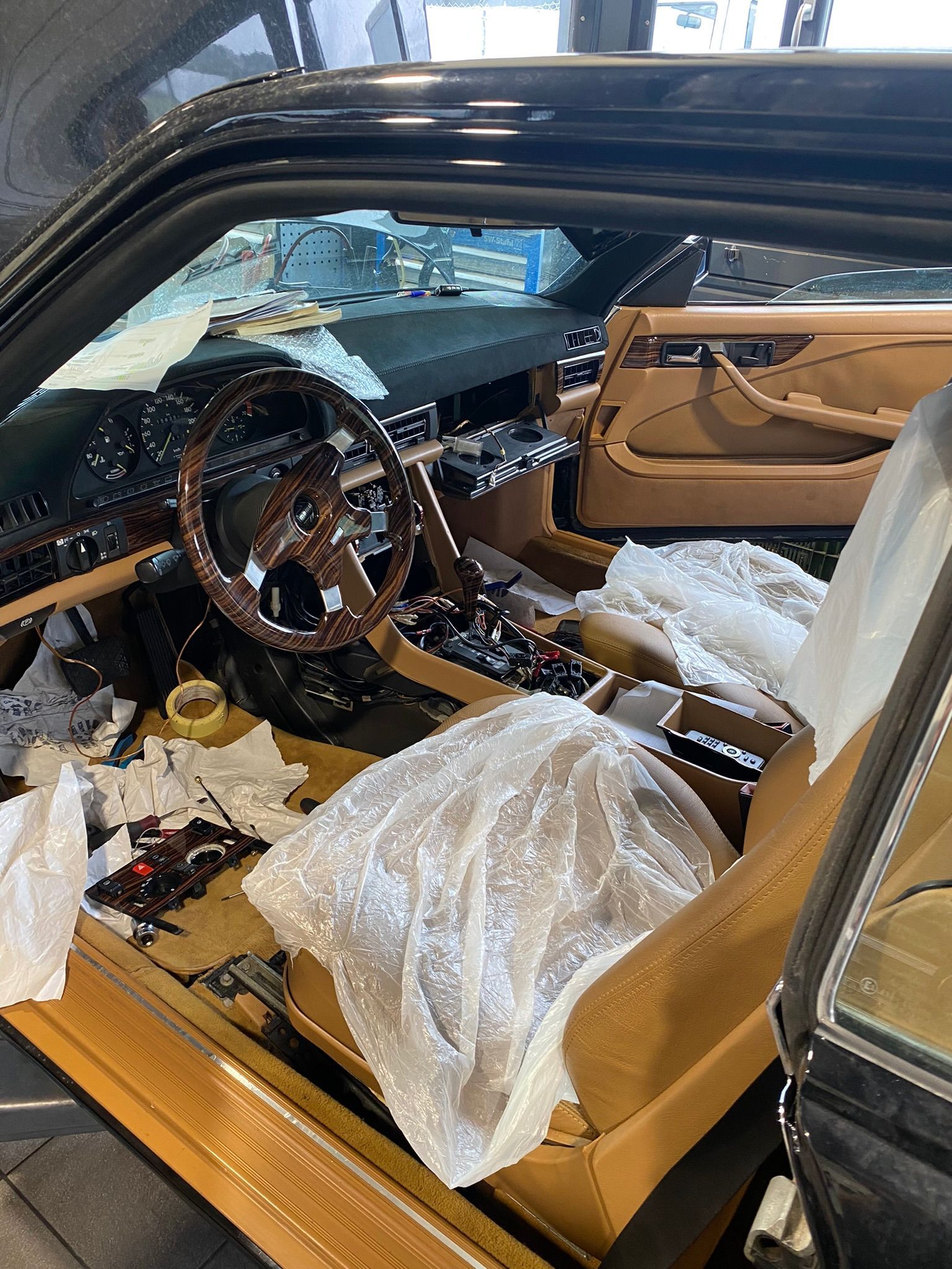 L'intérieur d'une voiture avec la porte ouverte et un volant en bois.