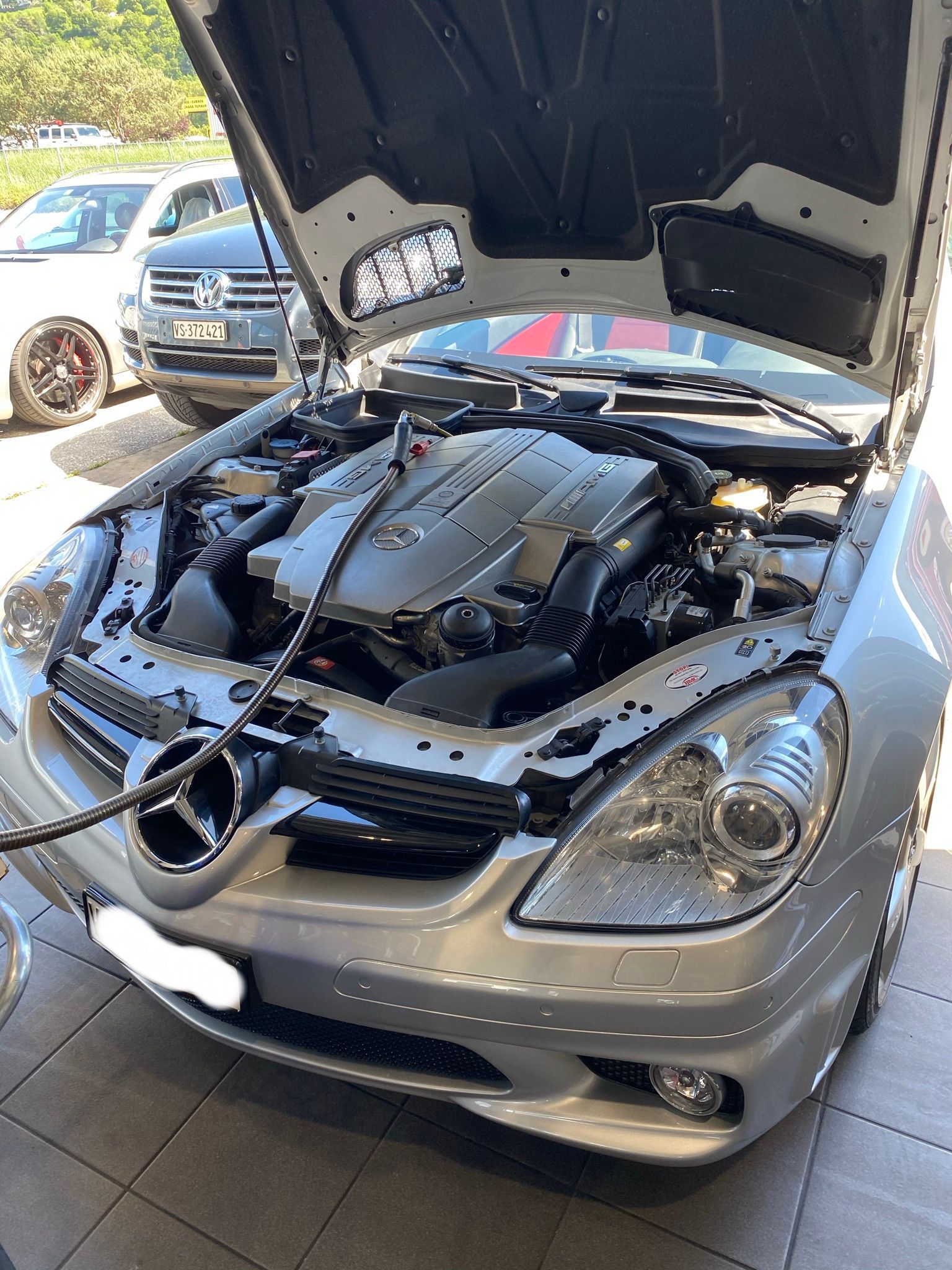 Le capot d'une Mercedes Benz est ouvert et le moteur est visible.