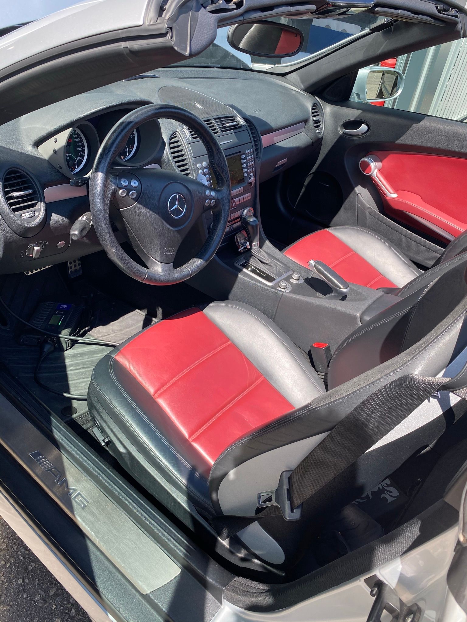 L'intérieur d'une voiture décapotable avec des sièges rouges et un volant.