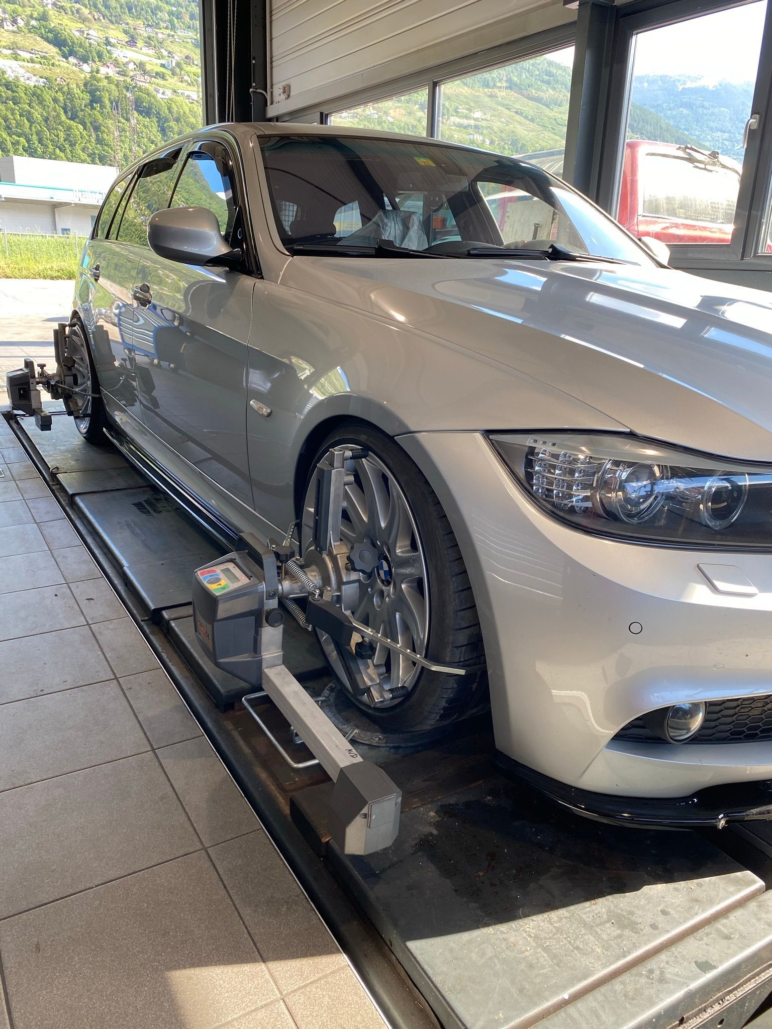 Une voiture argentée est assise sur un ascenseur dans un garage.