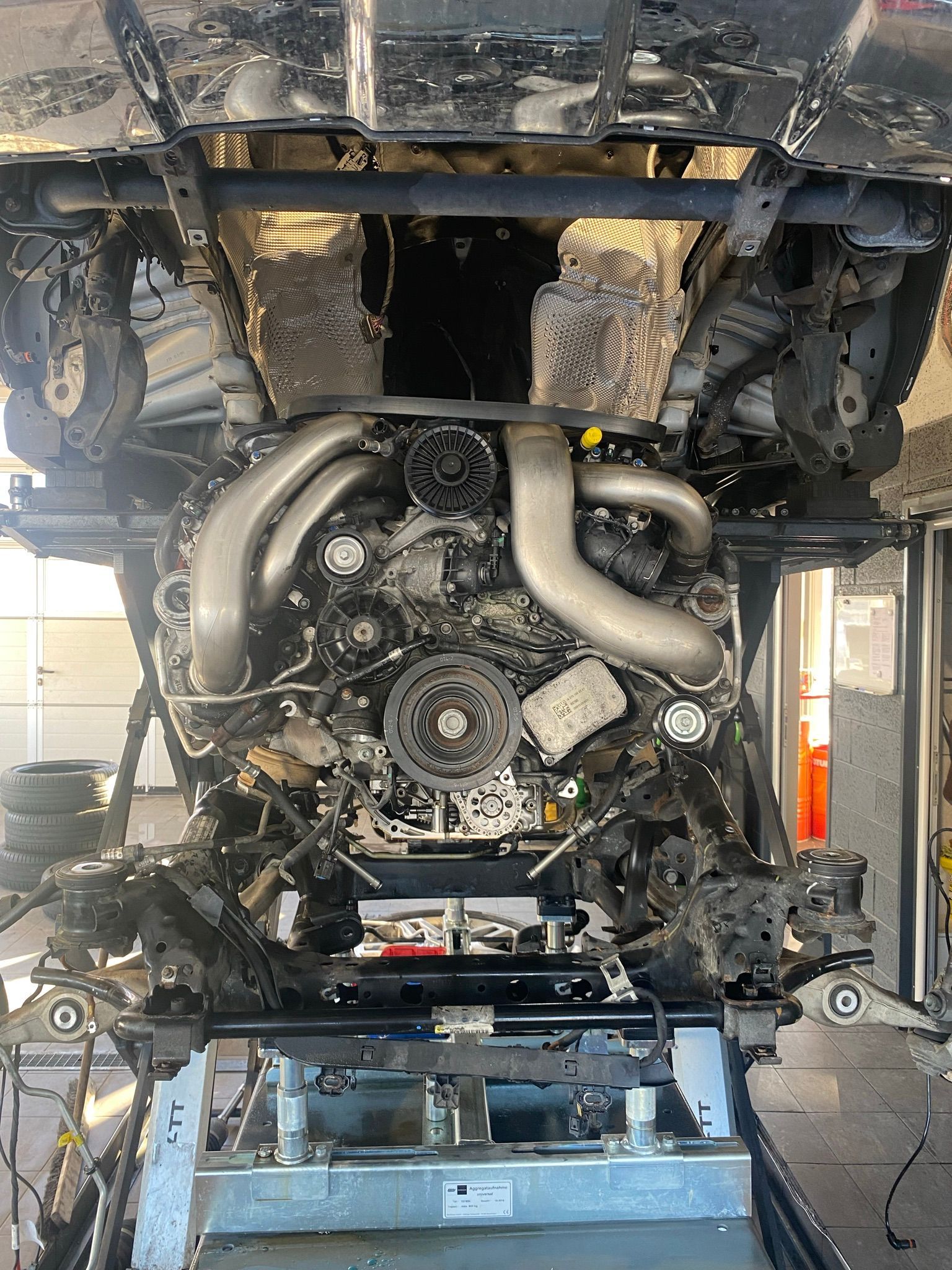 Un moteur de voiture est posé au sommet d’un ascenseur dans un garage.