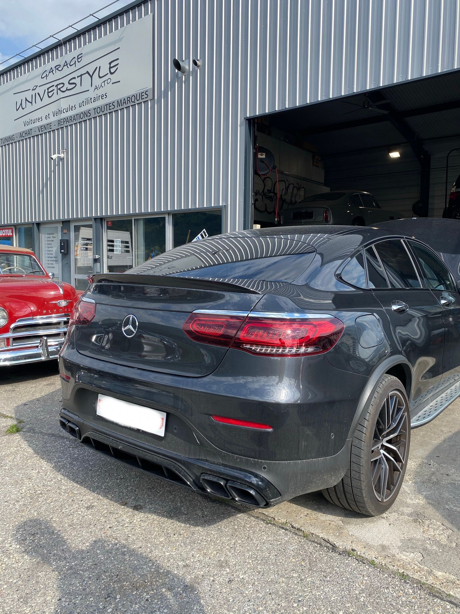 Une voiture noire est garée devant un immeuble.