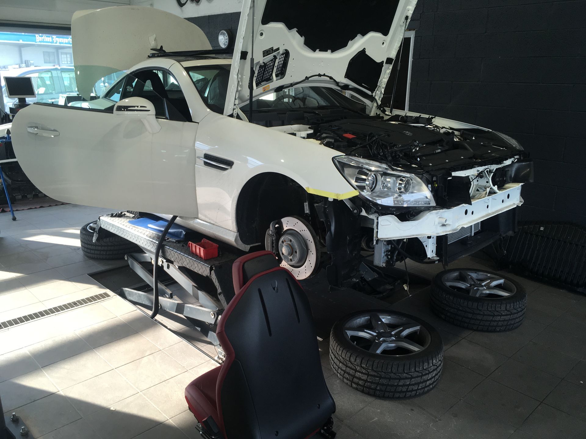 Une voiture est en travaux dans un garage avec le capot ouvert