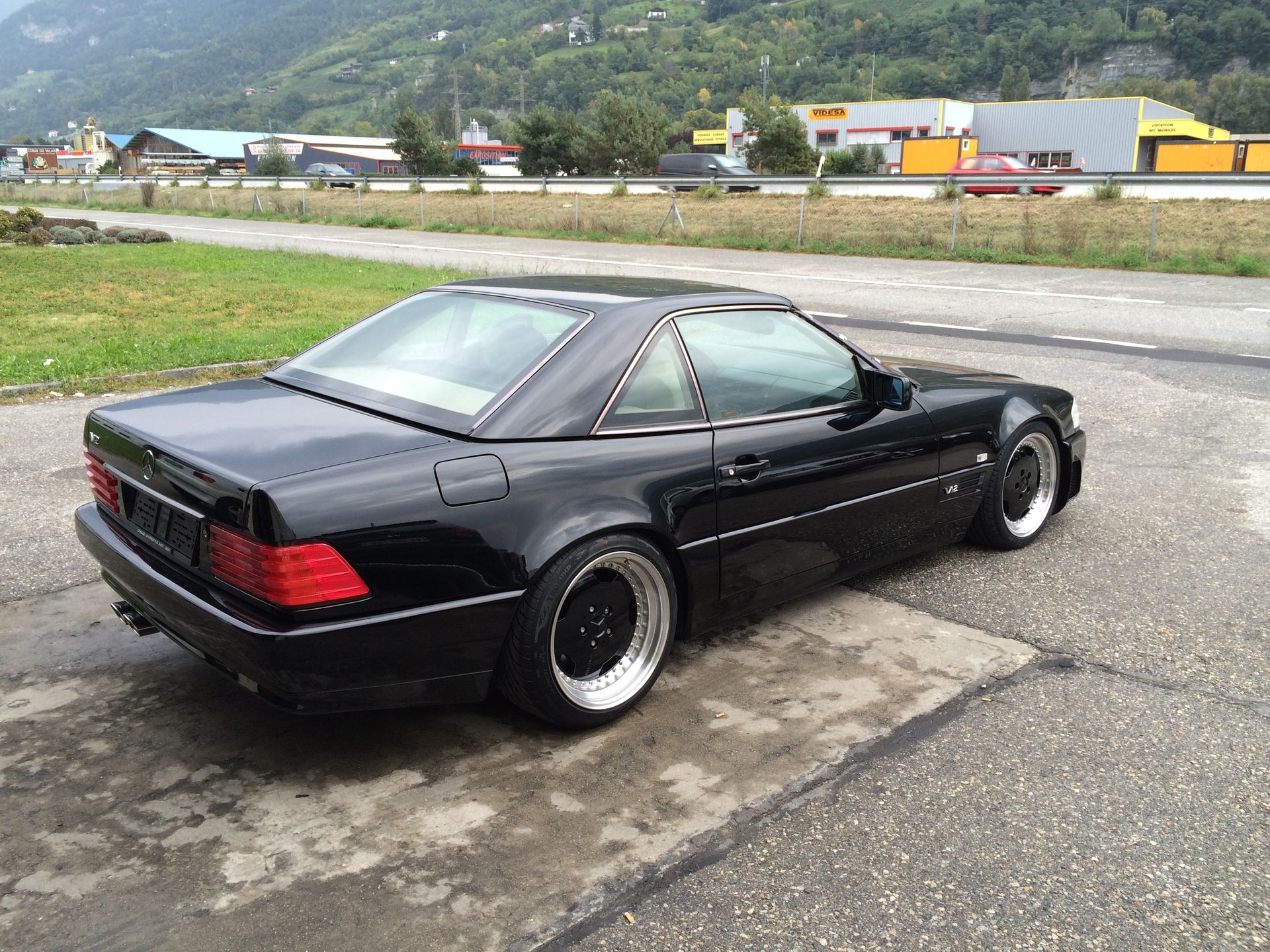 Une voiture de sport noire est garée sur le bord de la route.