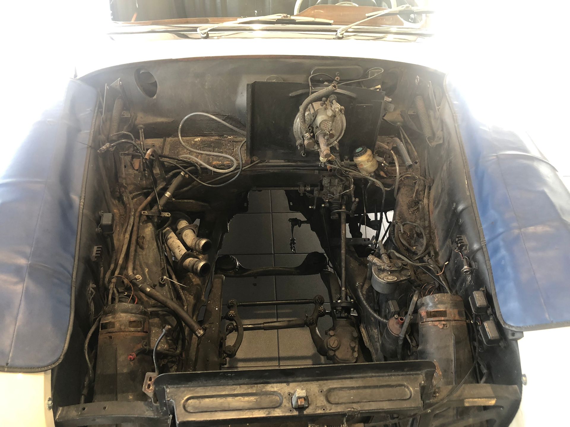 Le capot d'une voiture est ouvert et le moteur est visible.