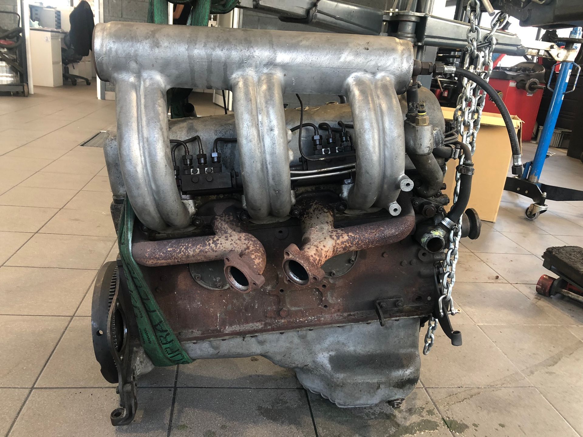 Un moteur de voiture repose sur un sol carrelé dans un garage.