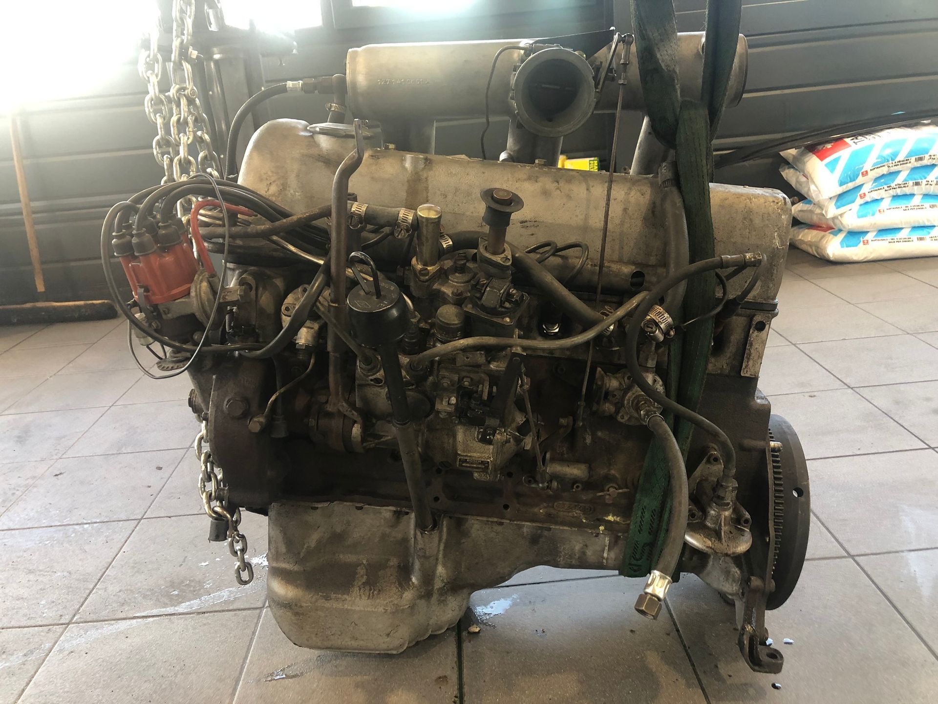 Un vieux moteur repose sur un sol carrelé dans un garage.